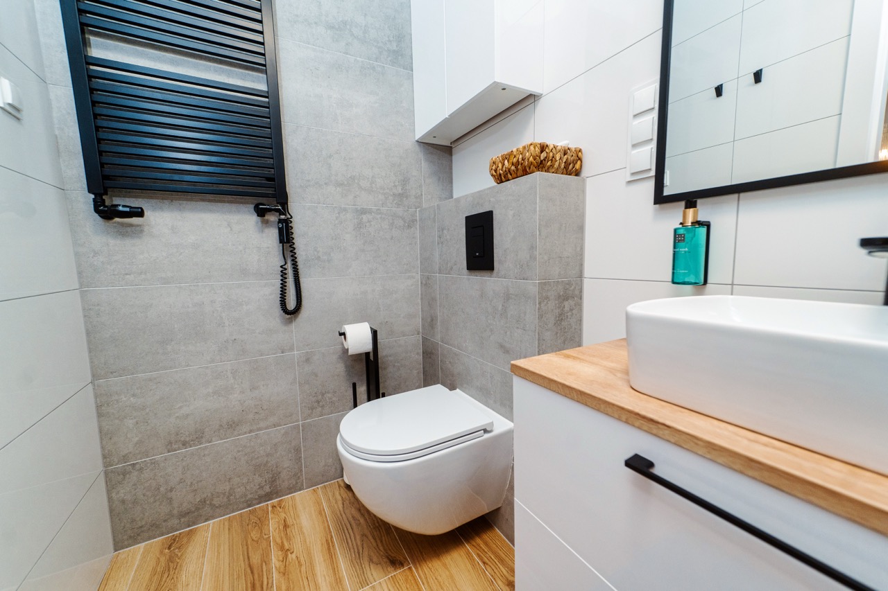 Nowoczesna łazienka z szarymi płytkami, WC i umywalką w apartamencie