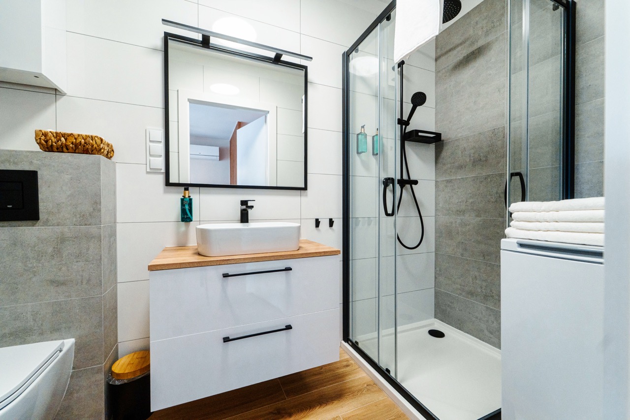 Łazienka z prysznicem, umywalką i pralką w apartamencie
