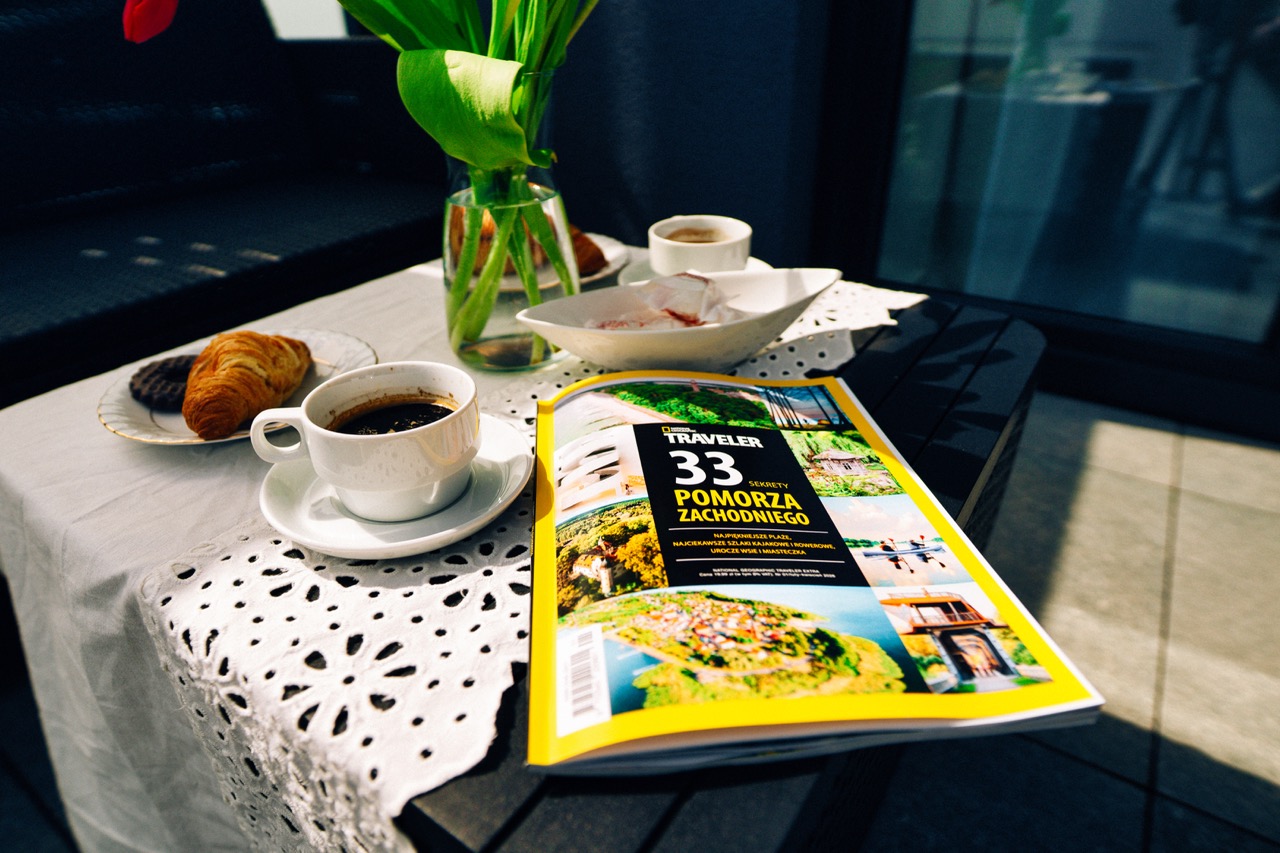 Stolik na tarasie z kawą, ciastkiem i magazynem podróżniczym