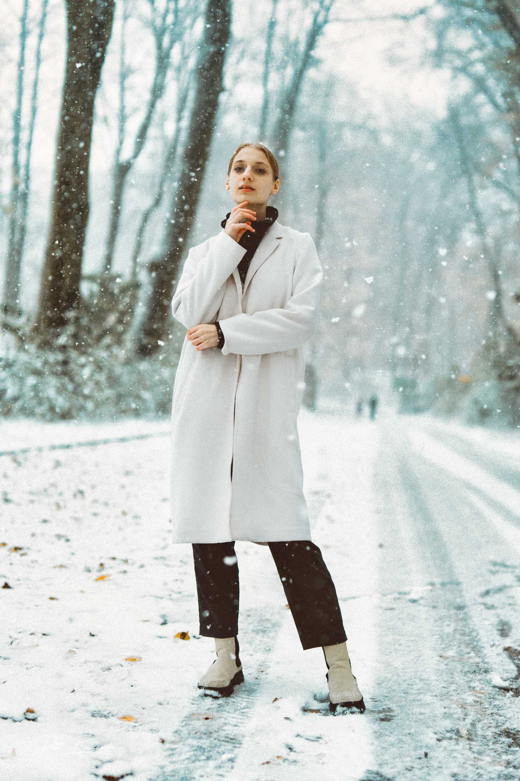 Portret zimowy modelki w białym płaszczu na tle ośnieżonej drogi w okolicach Jeziora Szmaragdowego w Szczecinie.