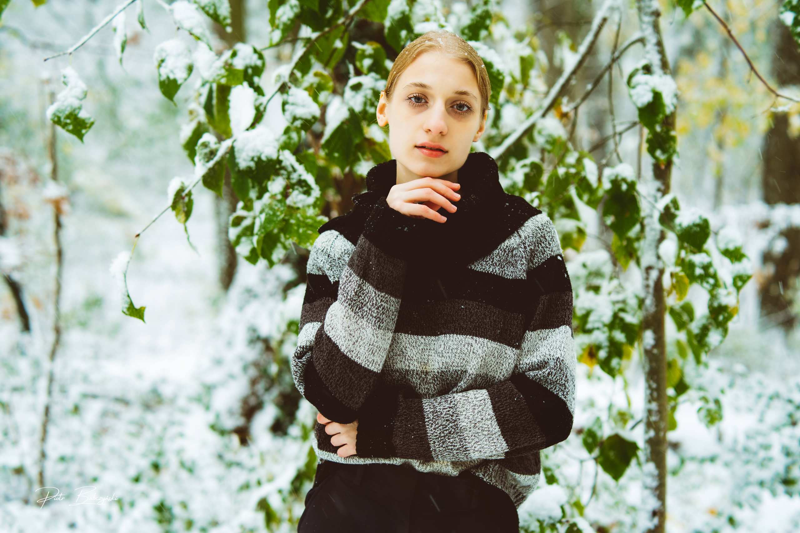 Modelka w zimowej scenerii, ubrana w sweter w paski, pozująca wśród ośnieżonych drzew w okolicach Jeziora Szmaragdowego w Szczecinie.