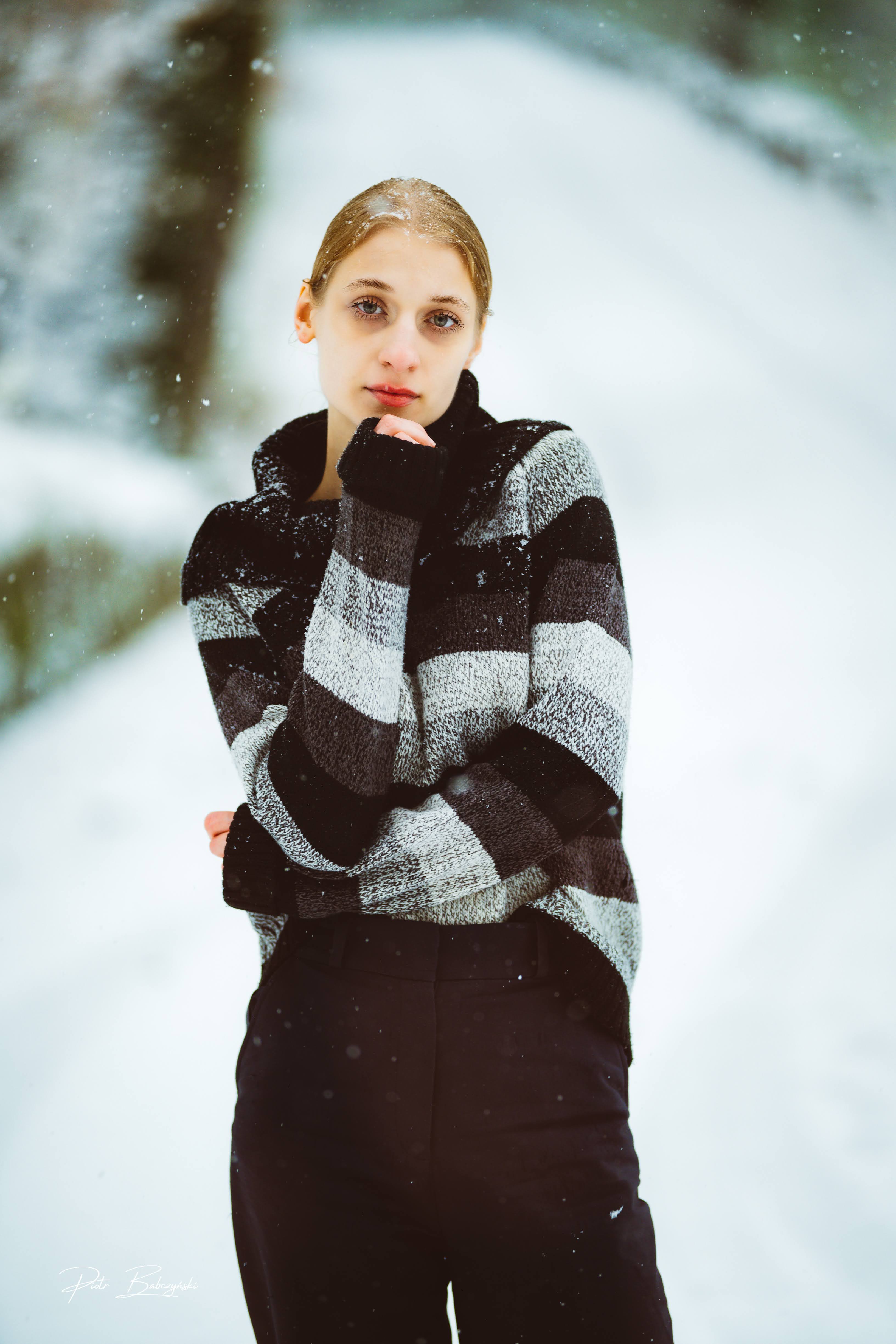 Modelka w zimowej scenerii, ubrana w sweter w paski, pozująca wśród ośnieżonych drzew w okolicach Jeziora Szmaragdowego w Szczecinie.
