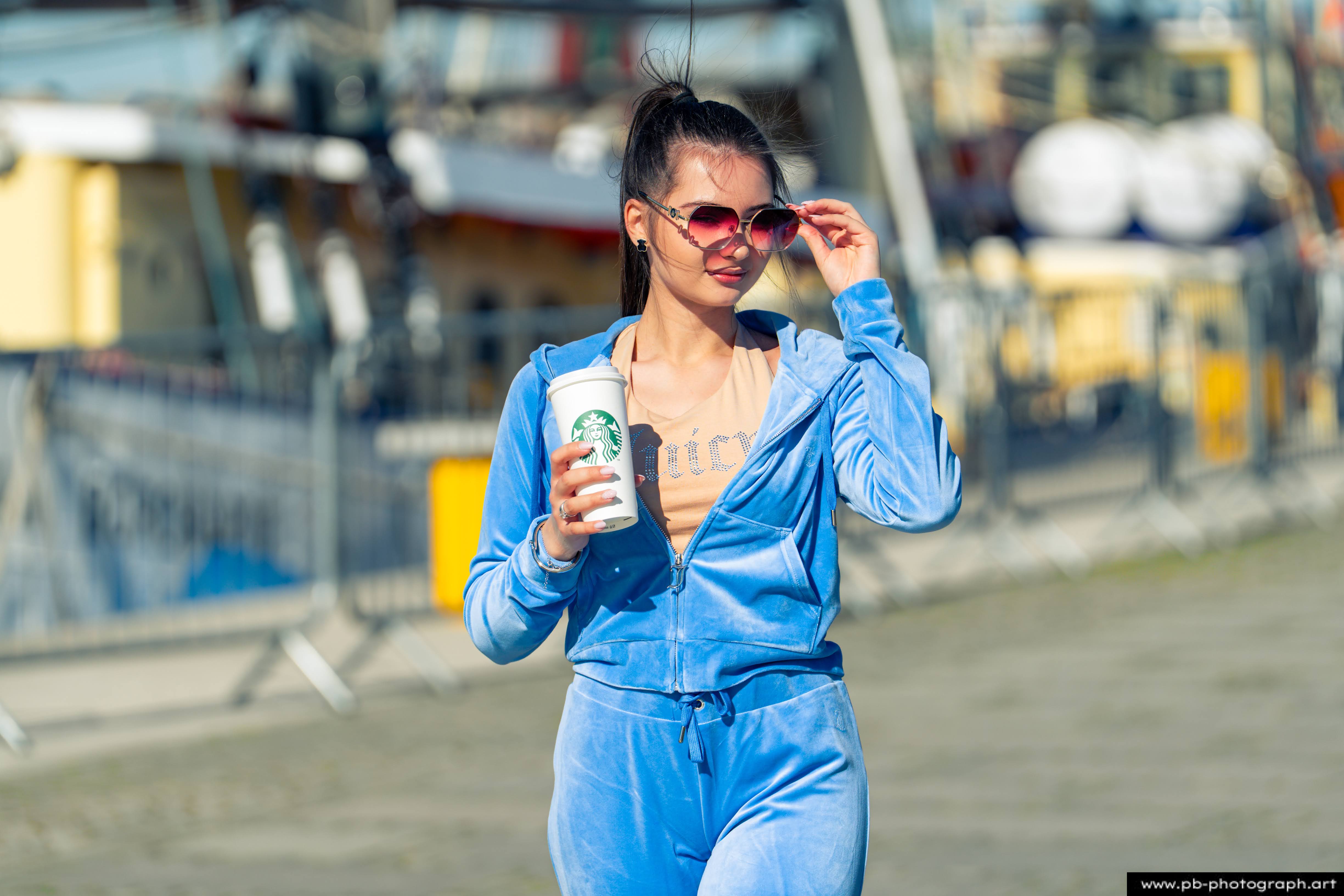 Fotografia produktowa na Łasztowni w Szczecinie — modelka w niebieskim dresie z kubkiem kawy.