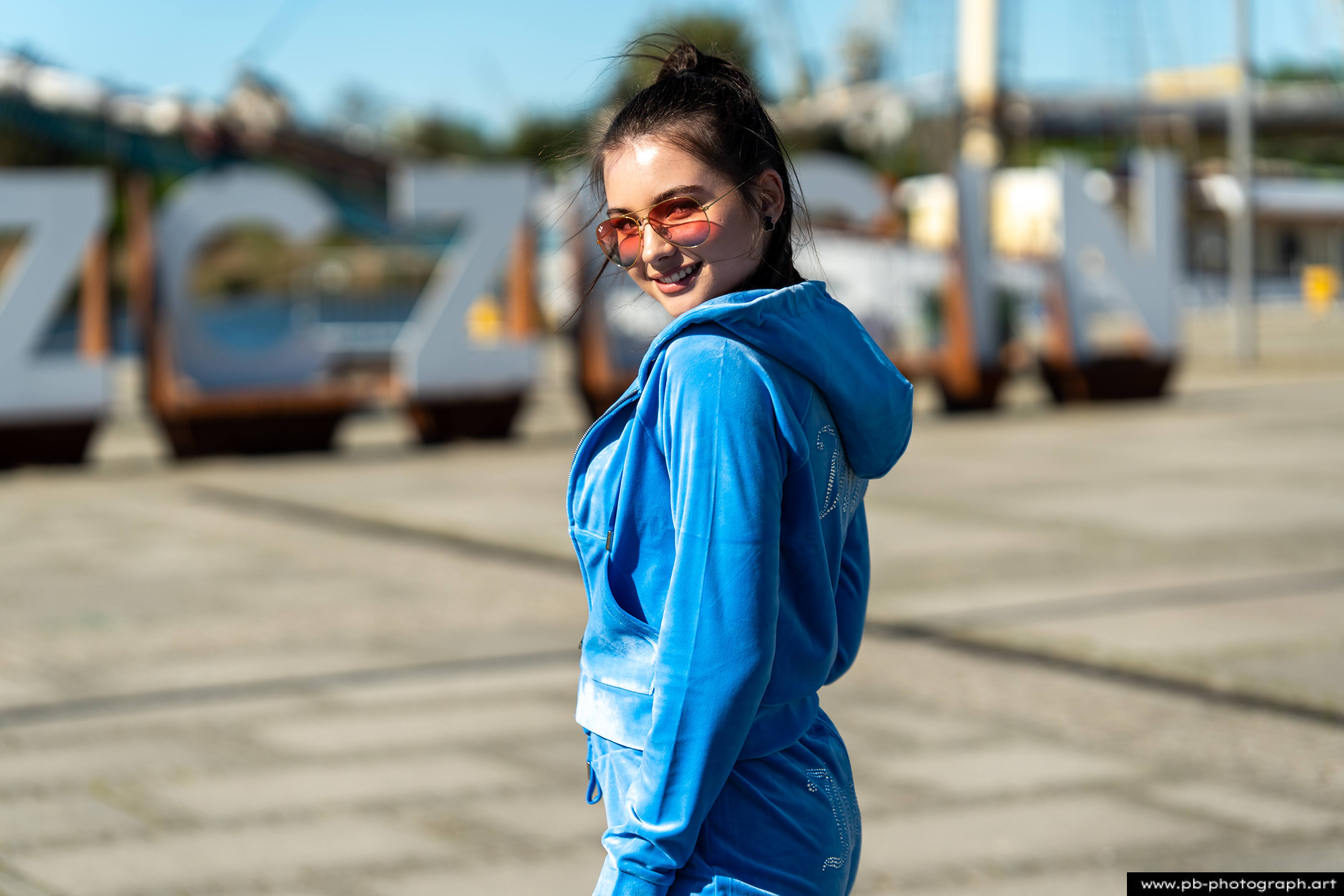 Fotografia produktowa na Łasztowni w Szczecinie — modelka w niebieskim dresie prezentuje najnowszą kolekcję ubrań.