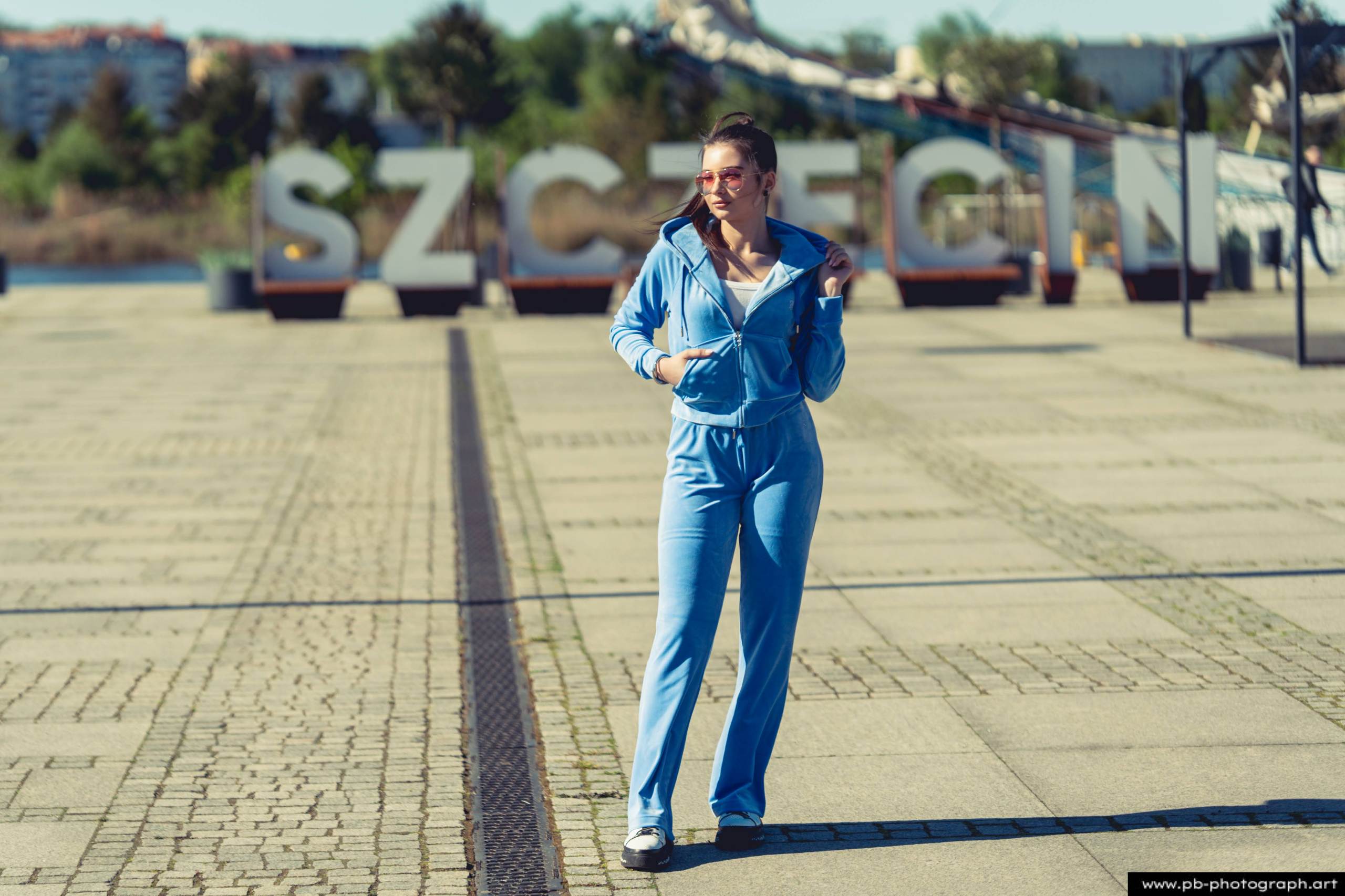 Fotografia produktowa na Łasztowni w Szczecinie — modelka w niebieskim dresie, podkreślająca unikalny styl kolekcji.