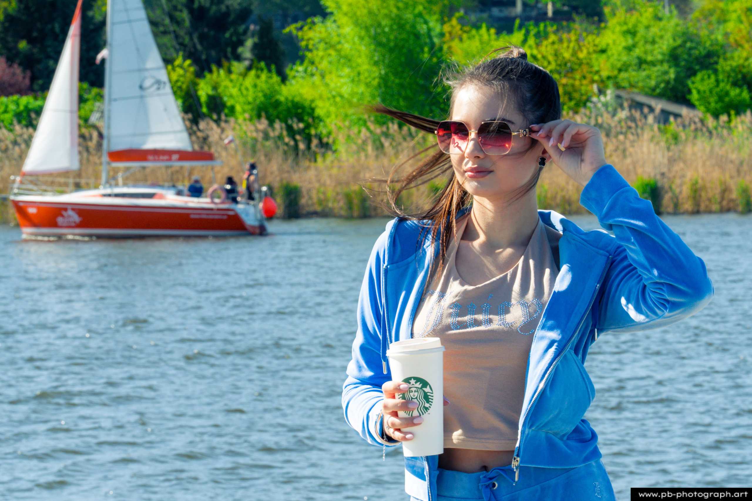 Fotografia produktowa na Łasztowni w Szczecinie — modelka w niebieskim dresie z kubkiem kawy w ręku.