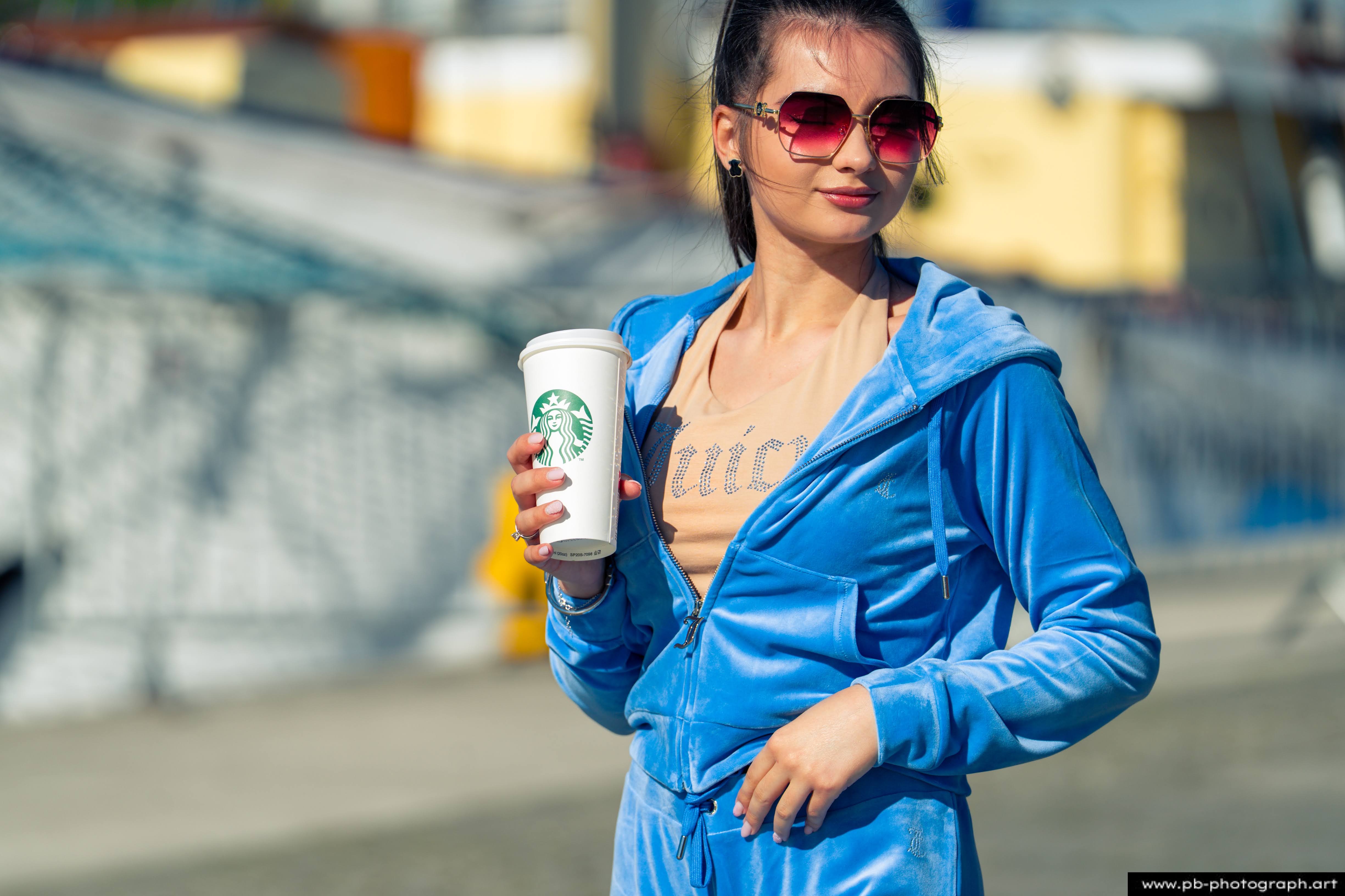 Fotografia produktowa na Łasztowni w Szczecinie — modelka w niebieskim dresie z kubkiem Starbucks.