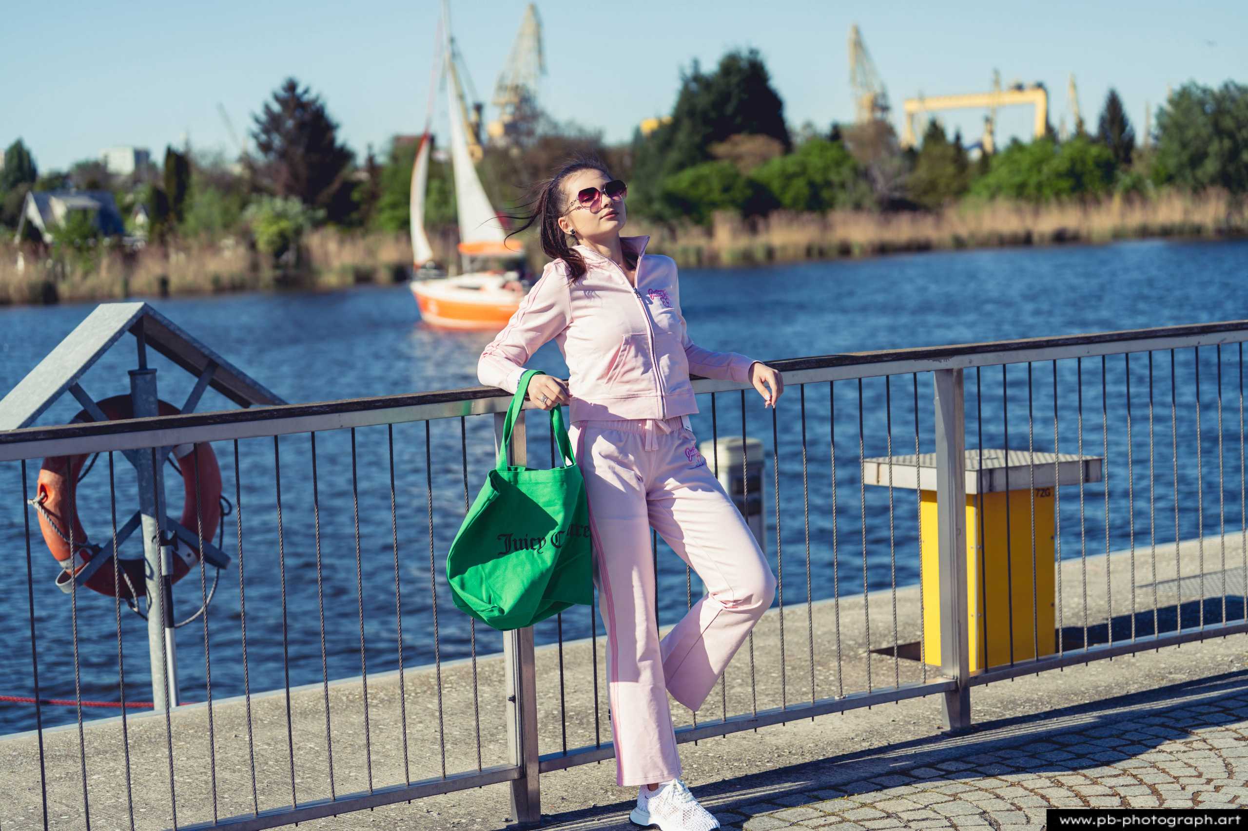 Fotografia produktowa na Łasztowni w Szczecinie — modelka w różowym komplecie z zieloną torbą.