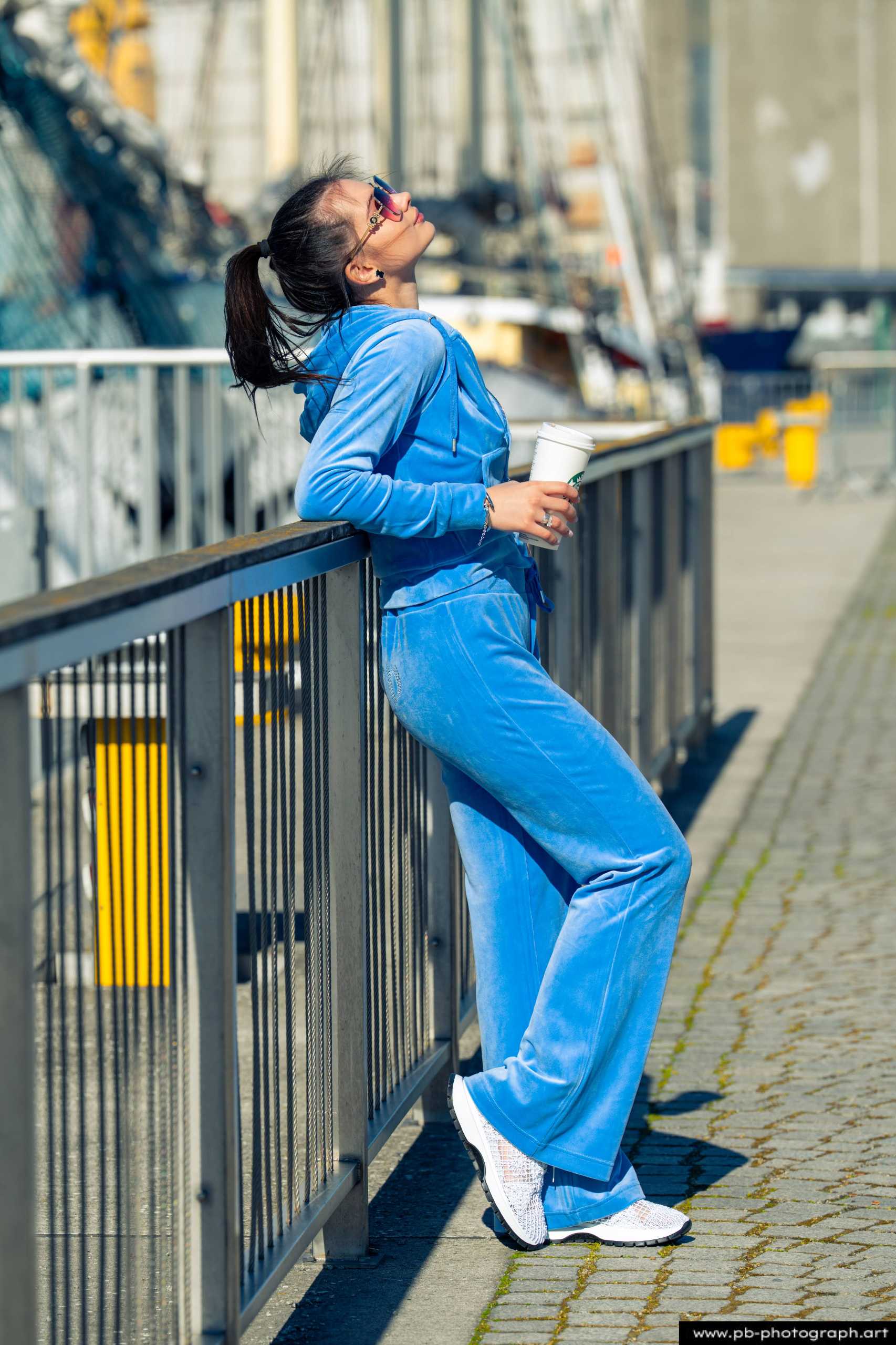 Fotografia produktowa na Łasztowni w Szczecinie — modelka w niebieskim dresie z kubkiem w dłoni.