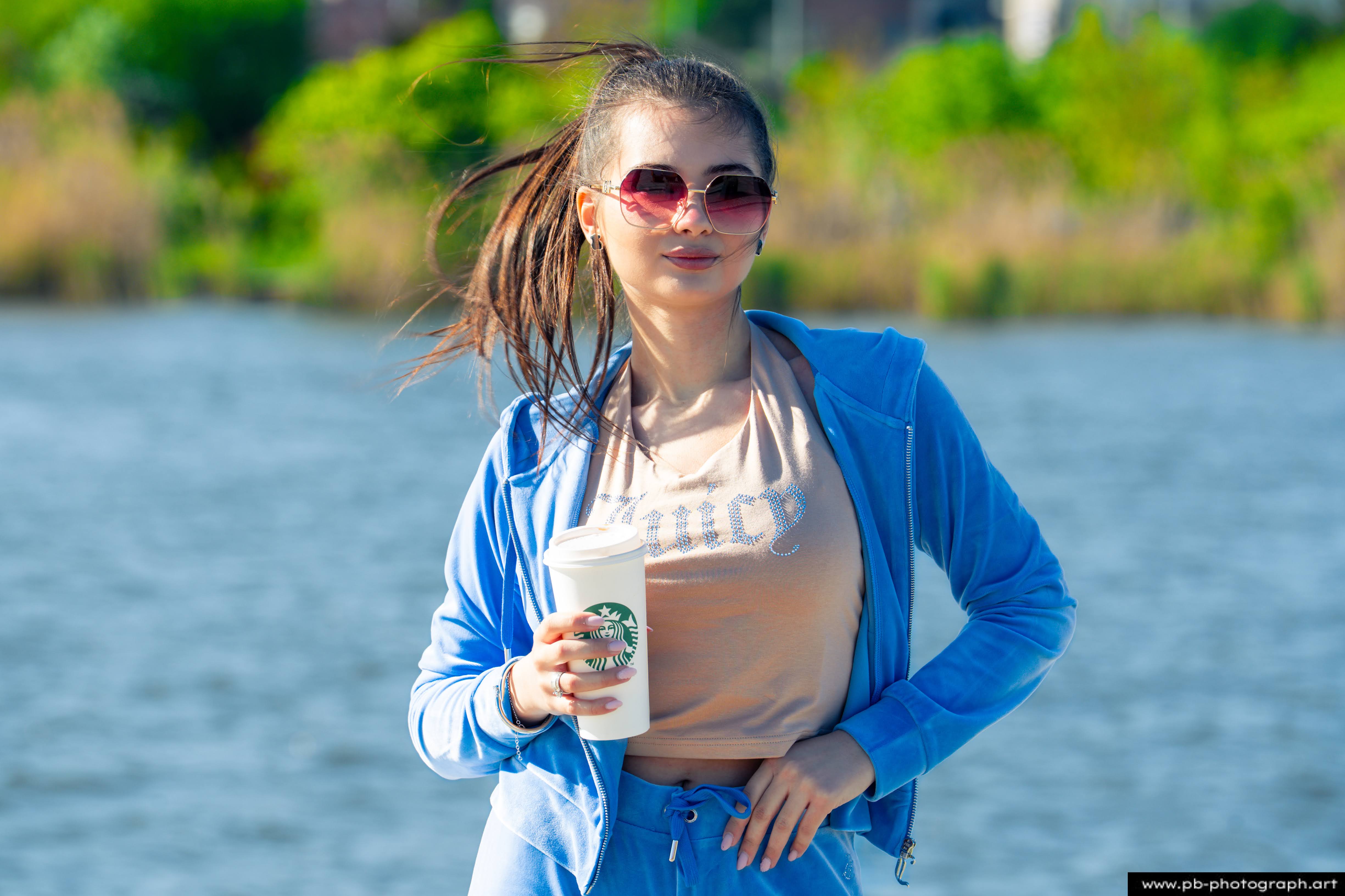 Fotografia produktowa na Łasztowni w Szczecinie — modelka w odzieży marki odzieżowej z kubkiem kawy.