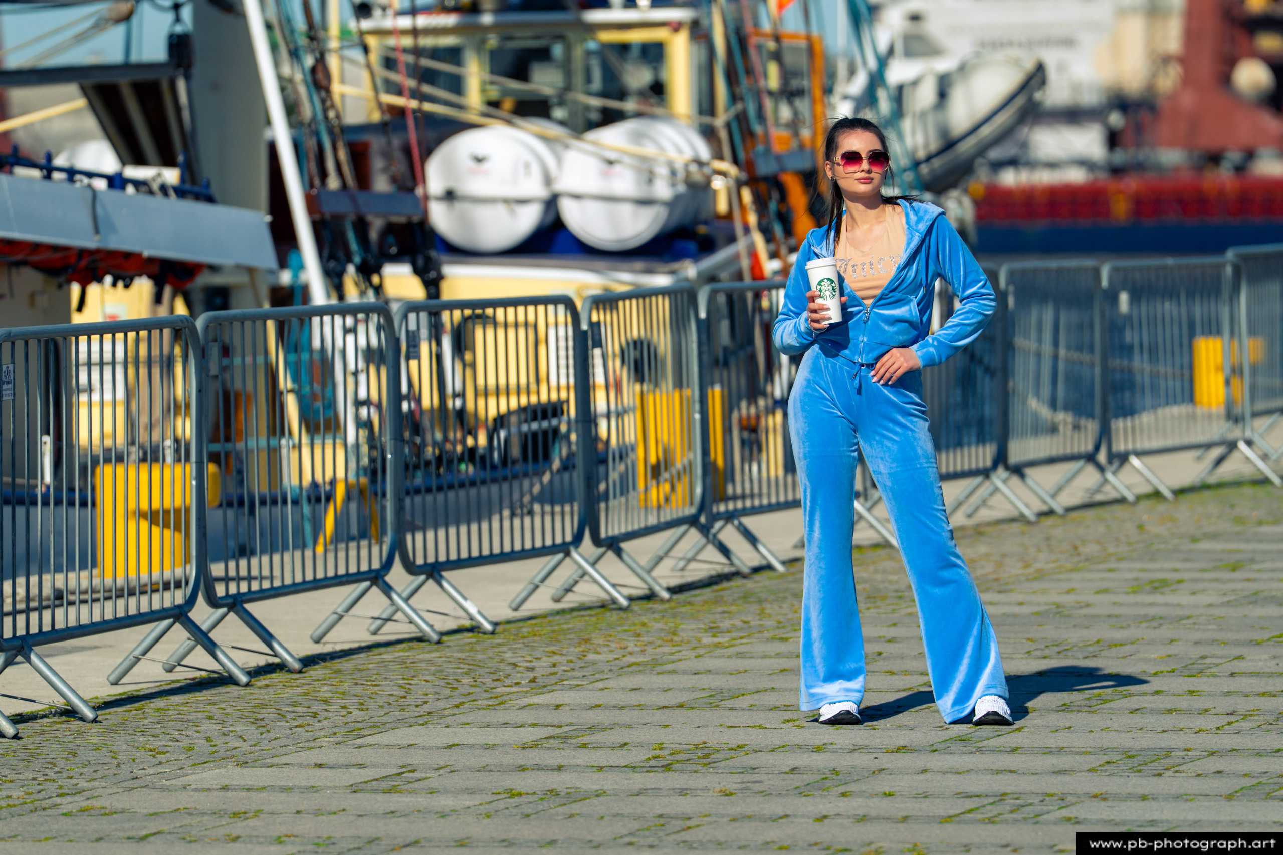 Fotografia produktowa na Łasztowni w Szczecinie — modelka w niebieskim dresie z napojem.