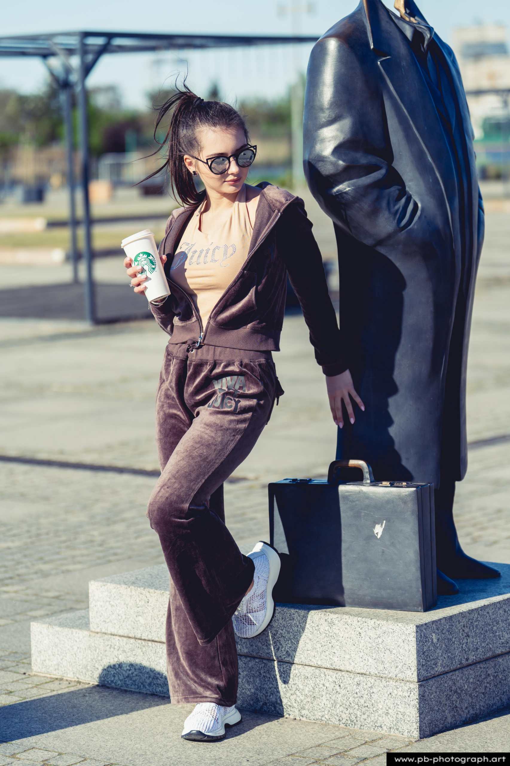 Fotografia produktowa na Łasztowni w Szczecinie — modelka w najnowszej kolekcji odzieżowej z kawą.