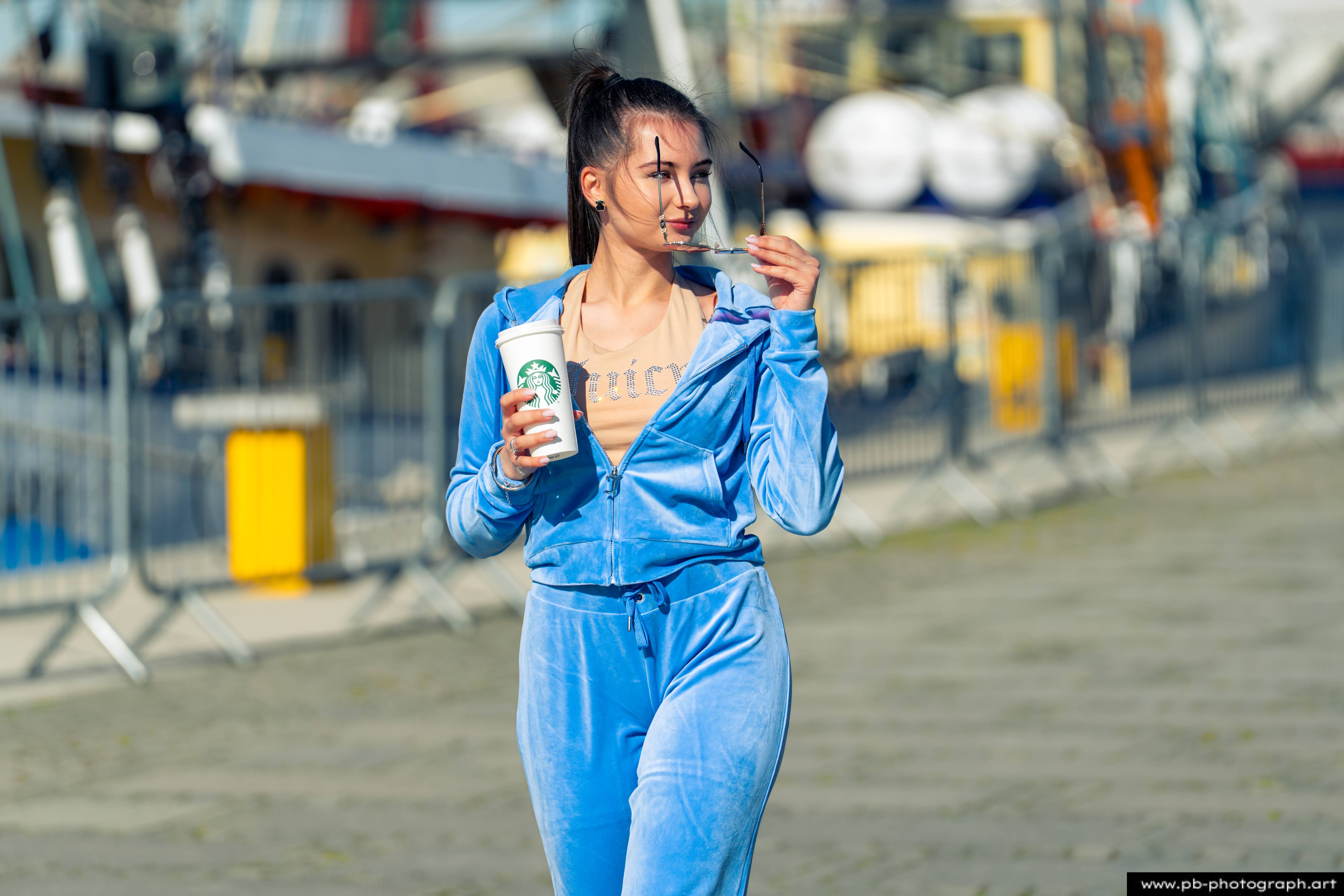 Fotografia produktowa na Łasztowni w Szczecinie — modelka w niebieskim dresie z kubkiem kawy.