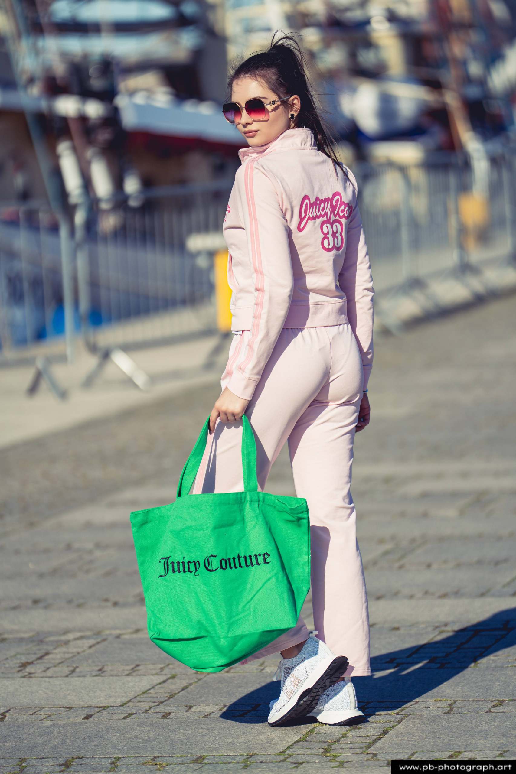 Fotografia produktowa na Łasztowni w Szczecinie — modelka w różowym dresie z torbą Juicy Couture.