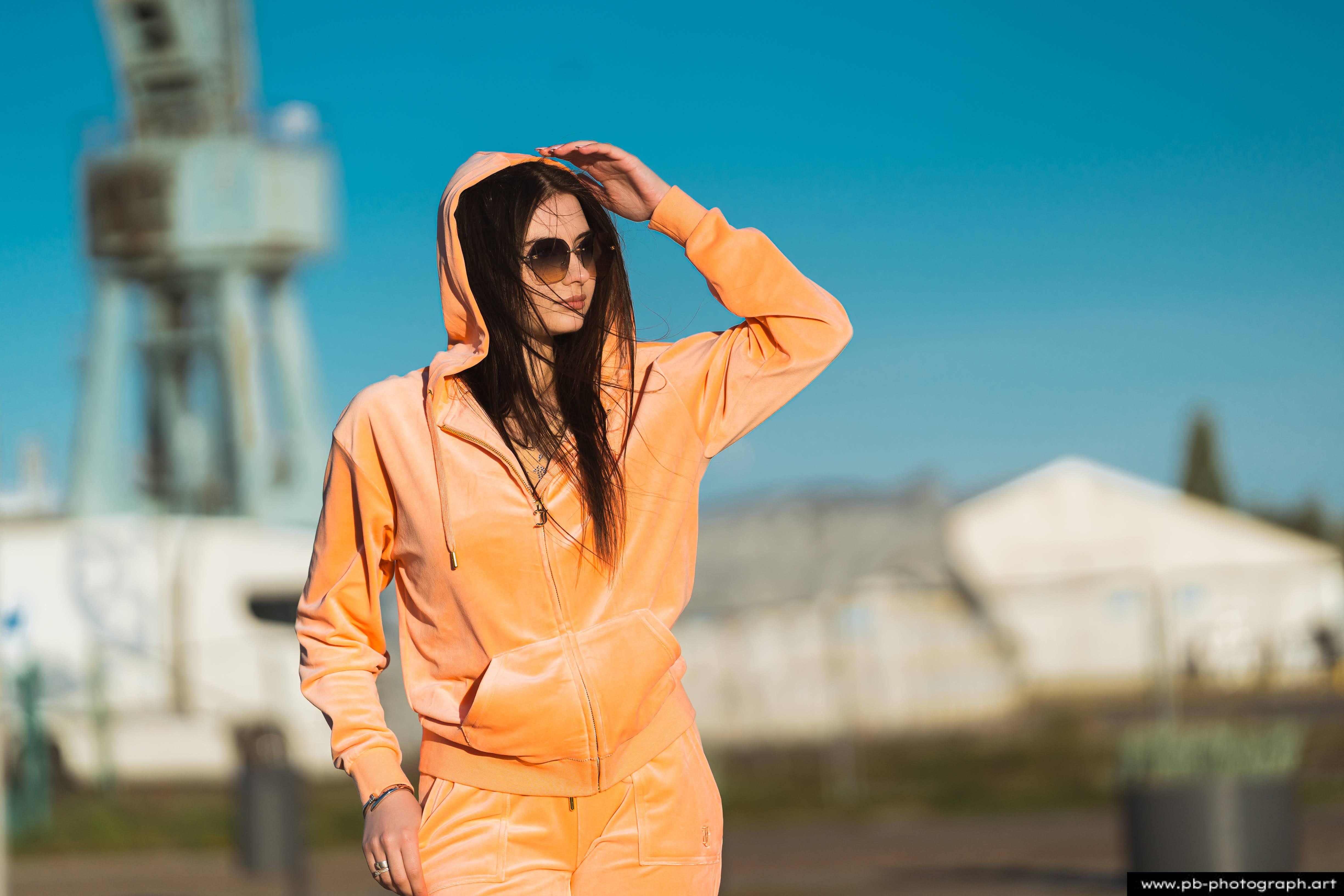 Fotografia produktowa na Łasztowni w Szczecinie — modelka w pomarańczowym dresie, podkreślająca unikalny styl marki.