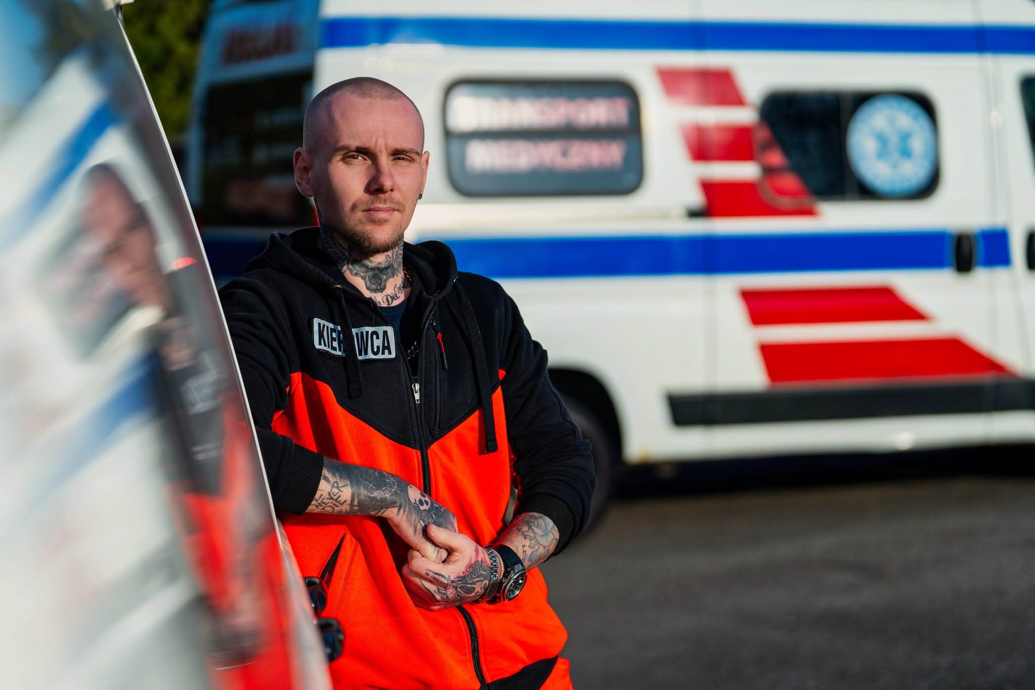 Mężczyzna w odzieży roboczej z logo RMED, stojący obok karetki w Szczecinie, podkreślający profesjonalizm zespołu.