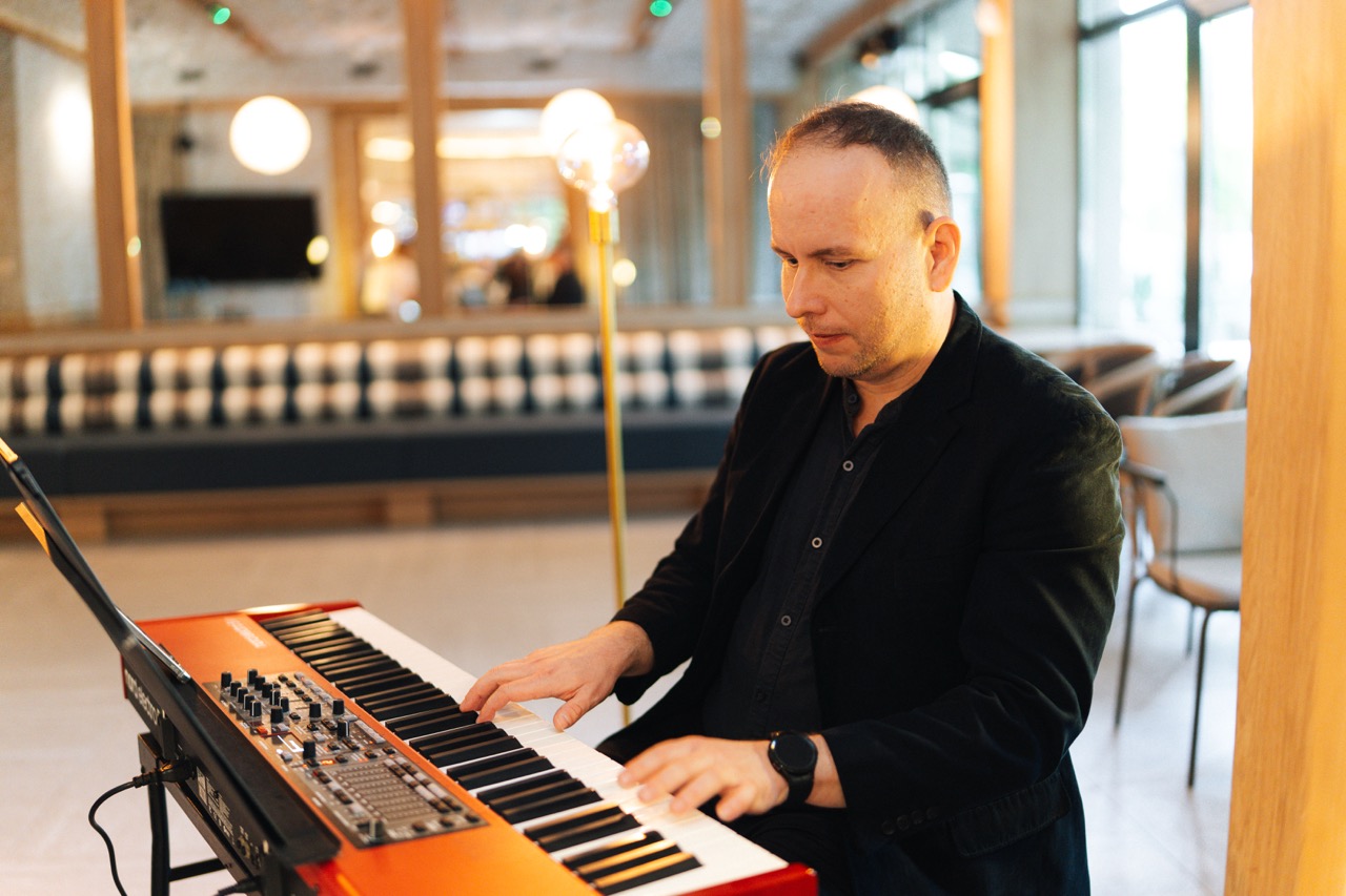 Fotografia eventowa z kolacji degustacyjnej w Szczecinie — muzyk grający na keyboardzie w luksusowym hotelu.