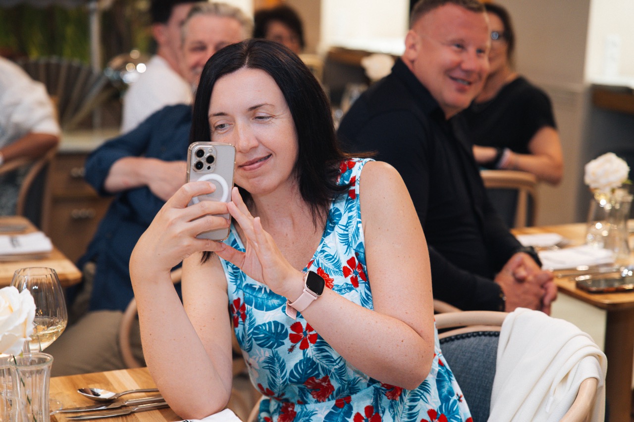 Fotografia eventowa z kolacji degustacyjnej z Karolem Okrasą w Szczecinie — goście bawią się i dokumentują chwile.
