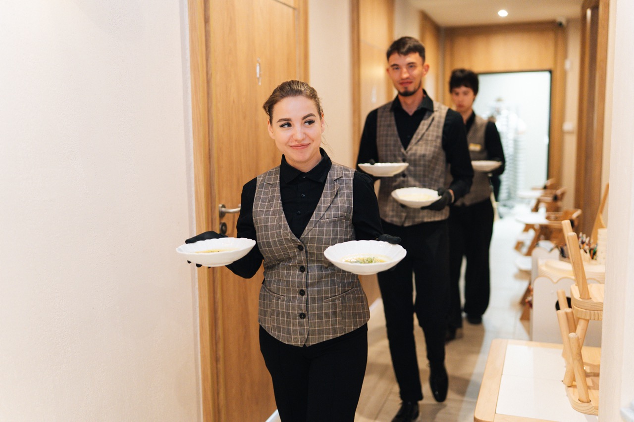 Fotografia eventowa z kolacji degustacyjnej w Szczecinie — kelnerzy serwujący dania w luksusowym hotelu.