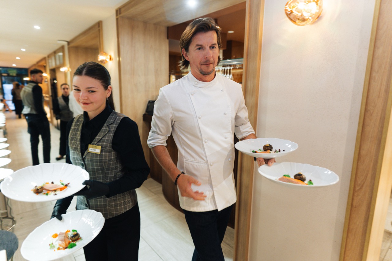 Fotografia eventowa z kolacji degustacyjnej w Szczecinie — Karol Okrasa serwuje dania gościom.