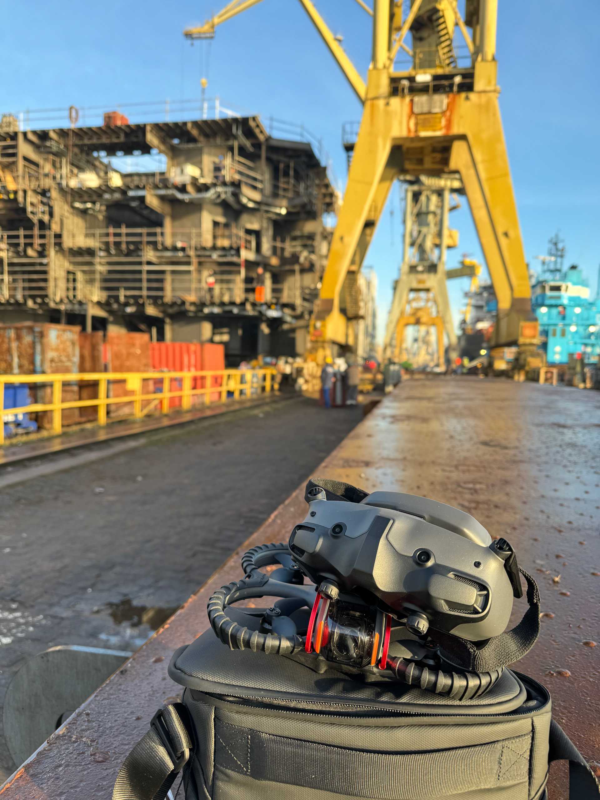 Gogle FPV i dron na torbie na tle żurawia i konstrukcji stoczni