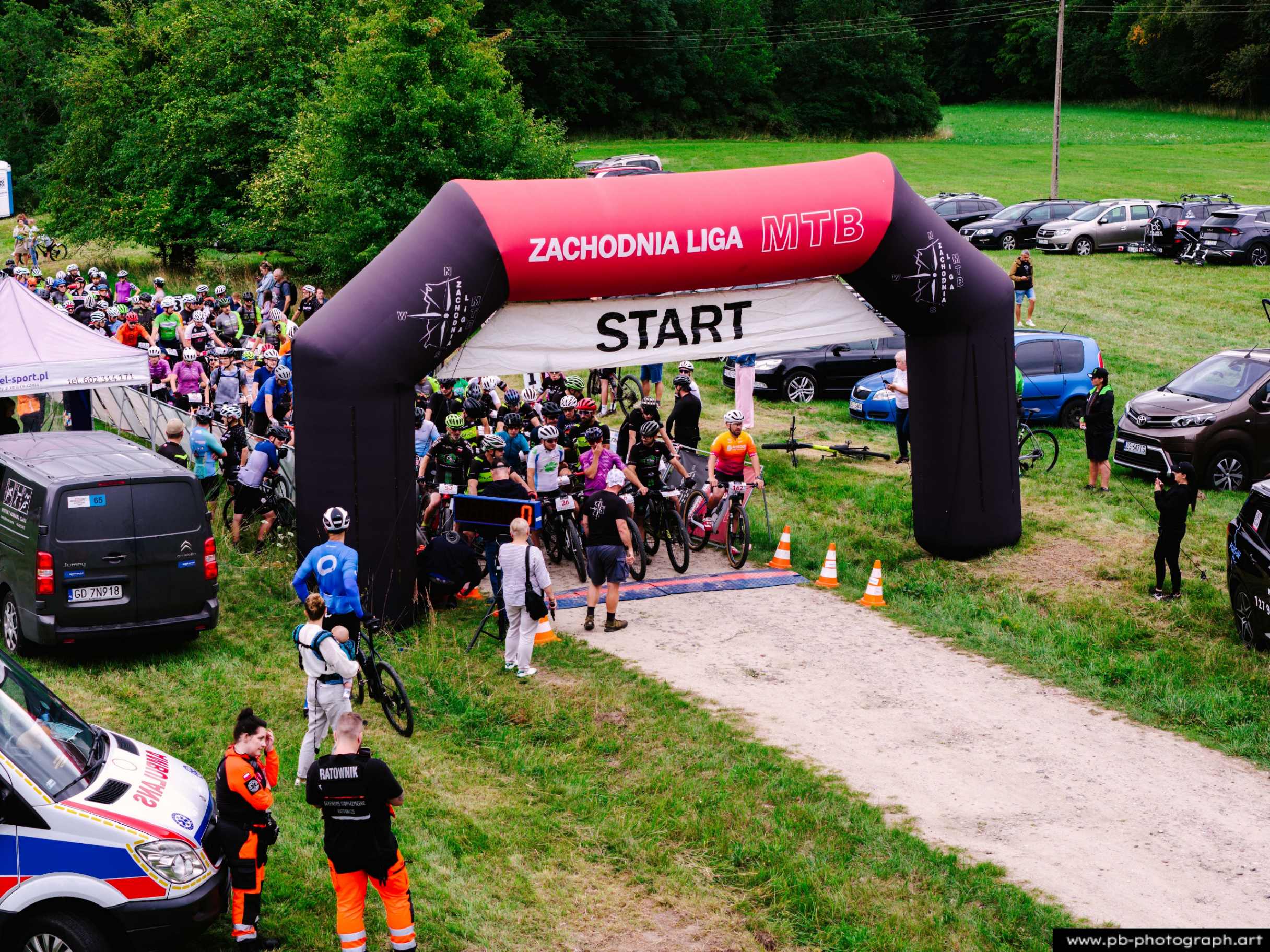 Fotografia z drona ukazująca start wyścigu MTB w Szczecinie, z zawodnikami przed bramą startową.