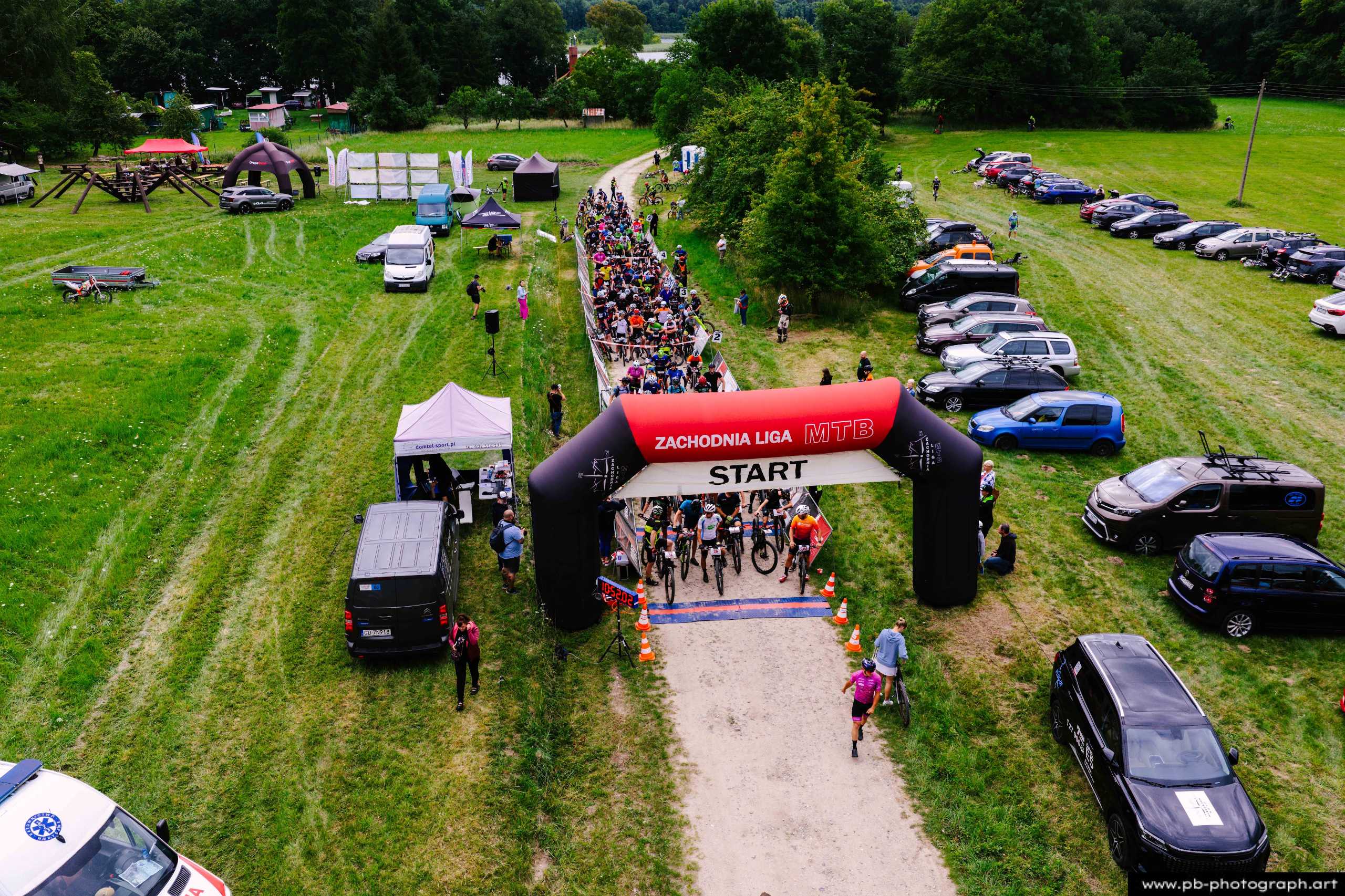 Ujęcie z drona na start wyścigu MTB w Szczecinie, z zawodnikami i samochodami w tle.