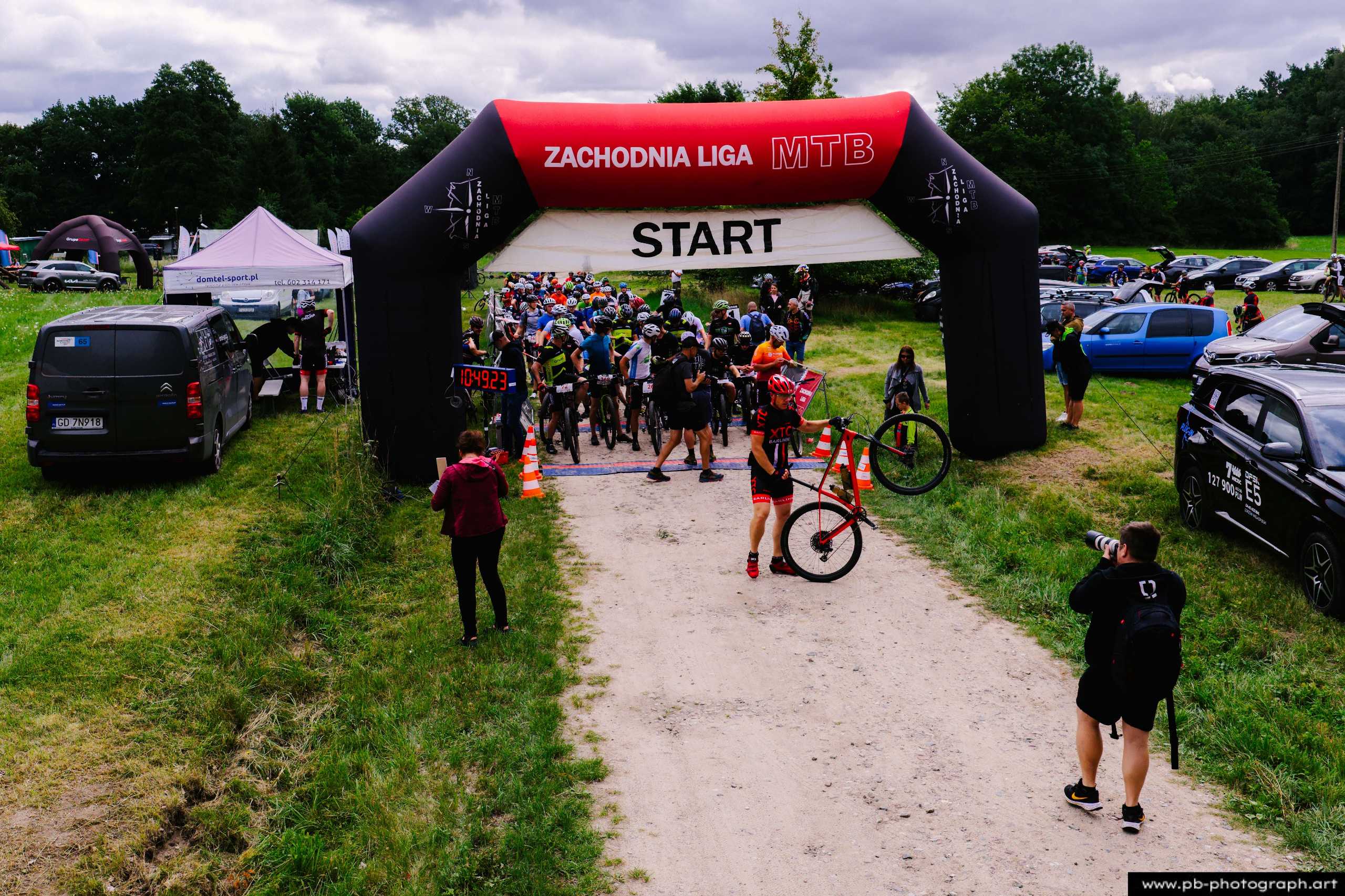 Ujęcie z drona na starcie wyścigu MTB w Szczecinie, z zawodnikami przygotowującymi się do startu pod bramą.