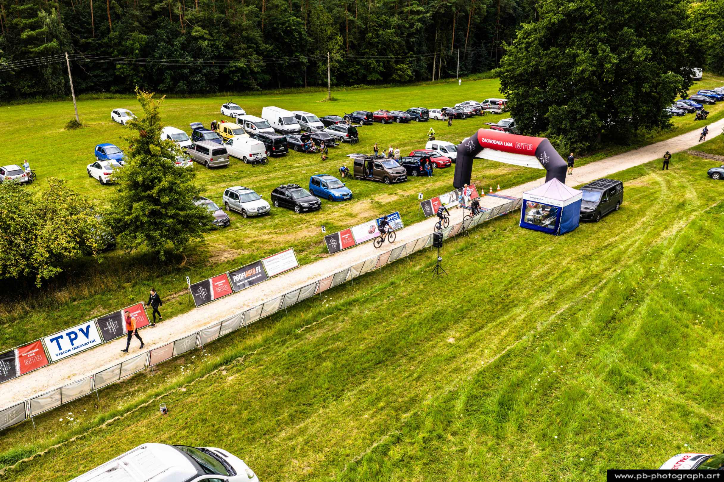 Ujęcie z drona na trasę wyścigu MTB w Szczecinie z zawodnikami przejeżdżającymi przez bramę startową.