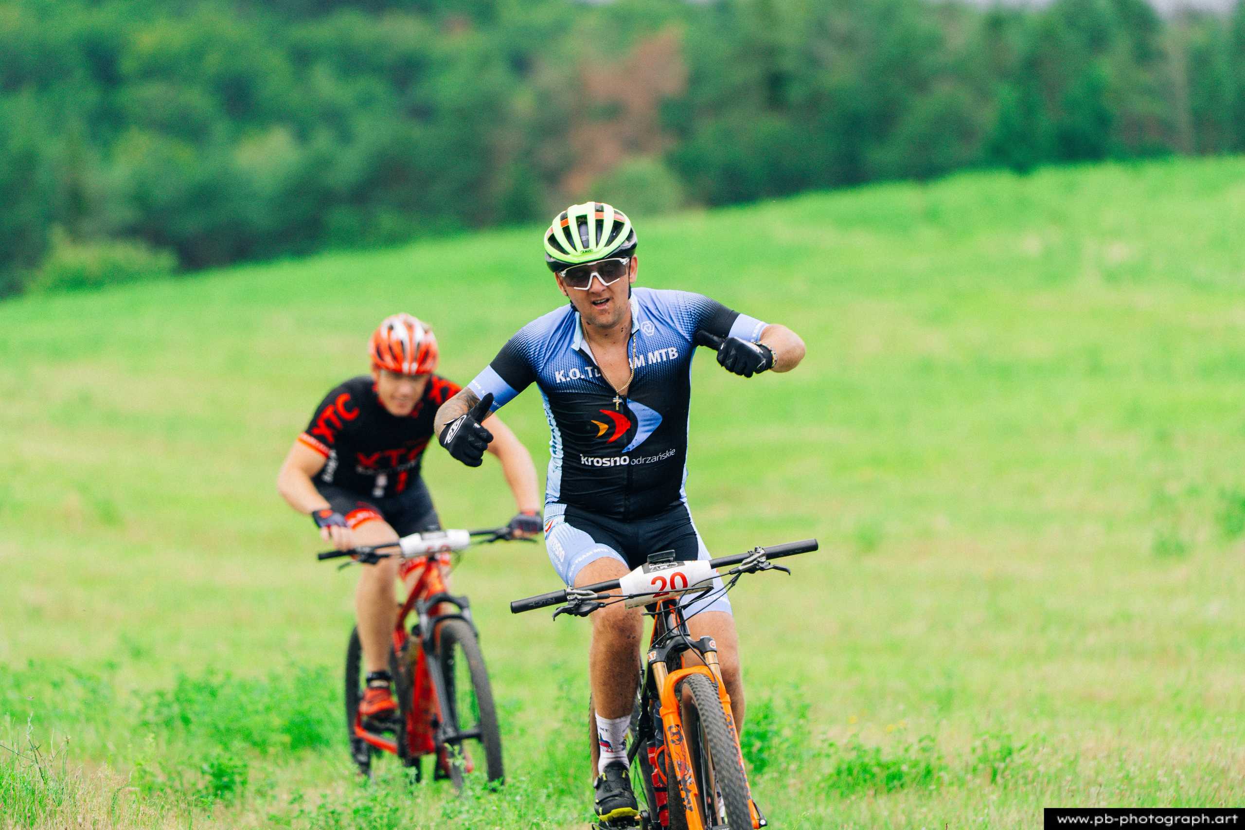 Zawodnicy MTB w trakcie wyścigu na zielonej trasie w Szczecinie, zbliżenie na kolarza w akcji.