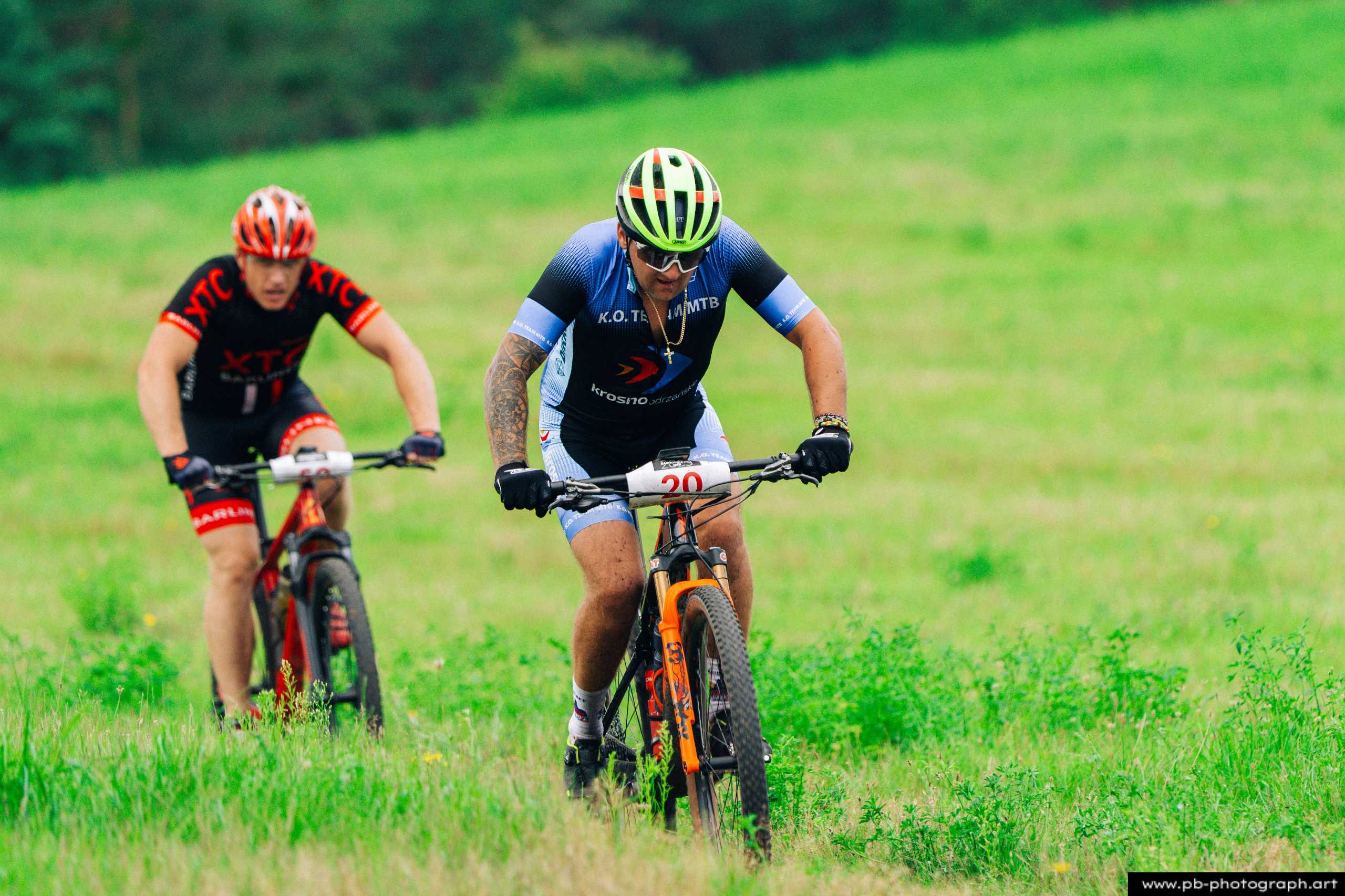 Ujęcie z drona podczas wyścigów MTB w Szczecinie — zawodnicy pokonujący trudny odcinek trasy w zielonym terenie.