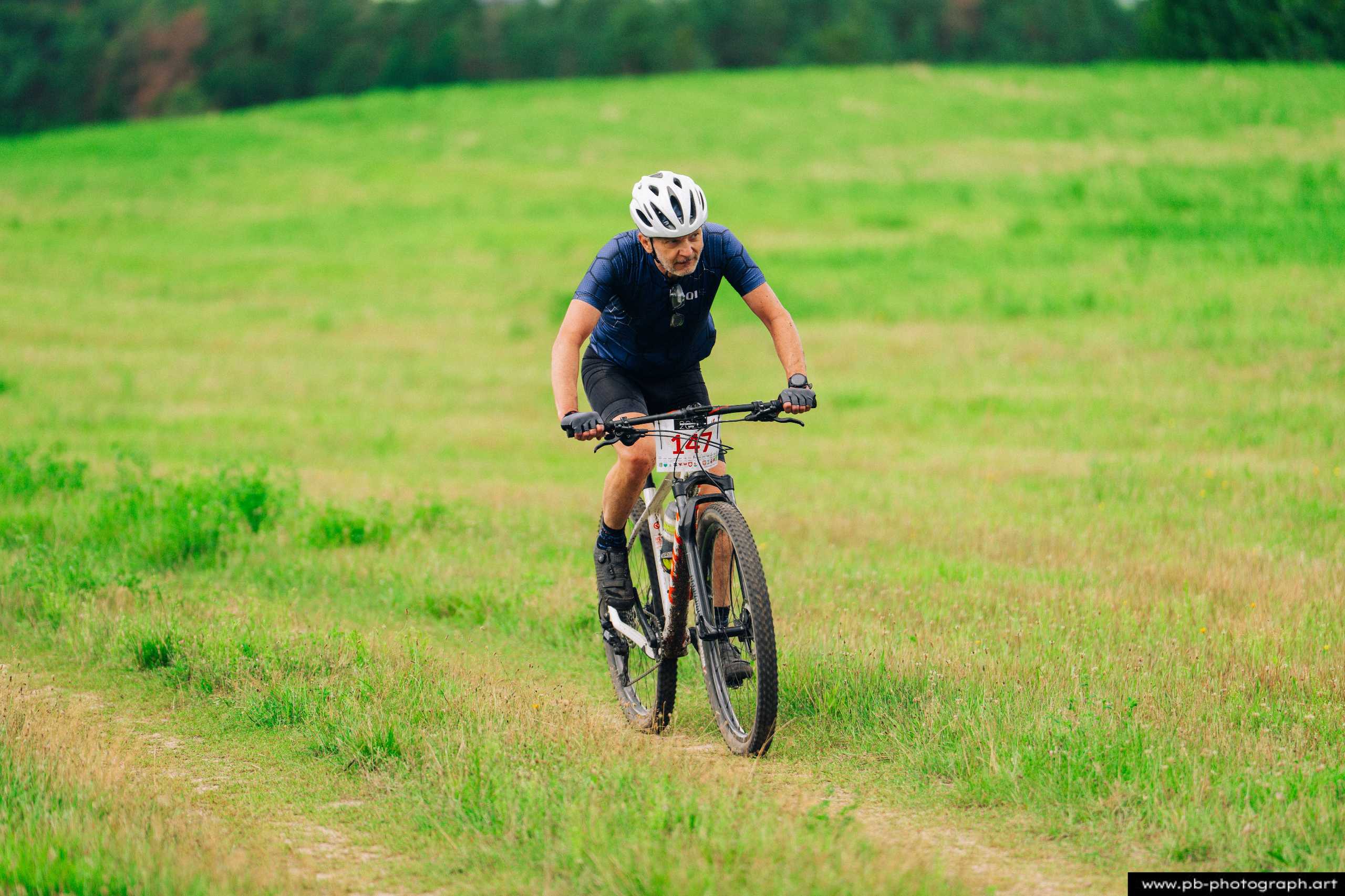 Zawodnik MTB w trakcie wyścigu na zielonej trasie w Szczecinie, zbliżenie na jazdę w terenie.