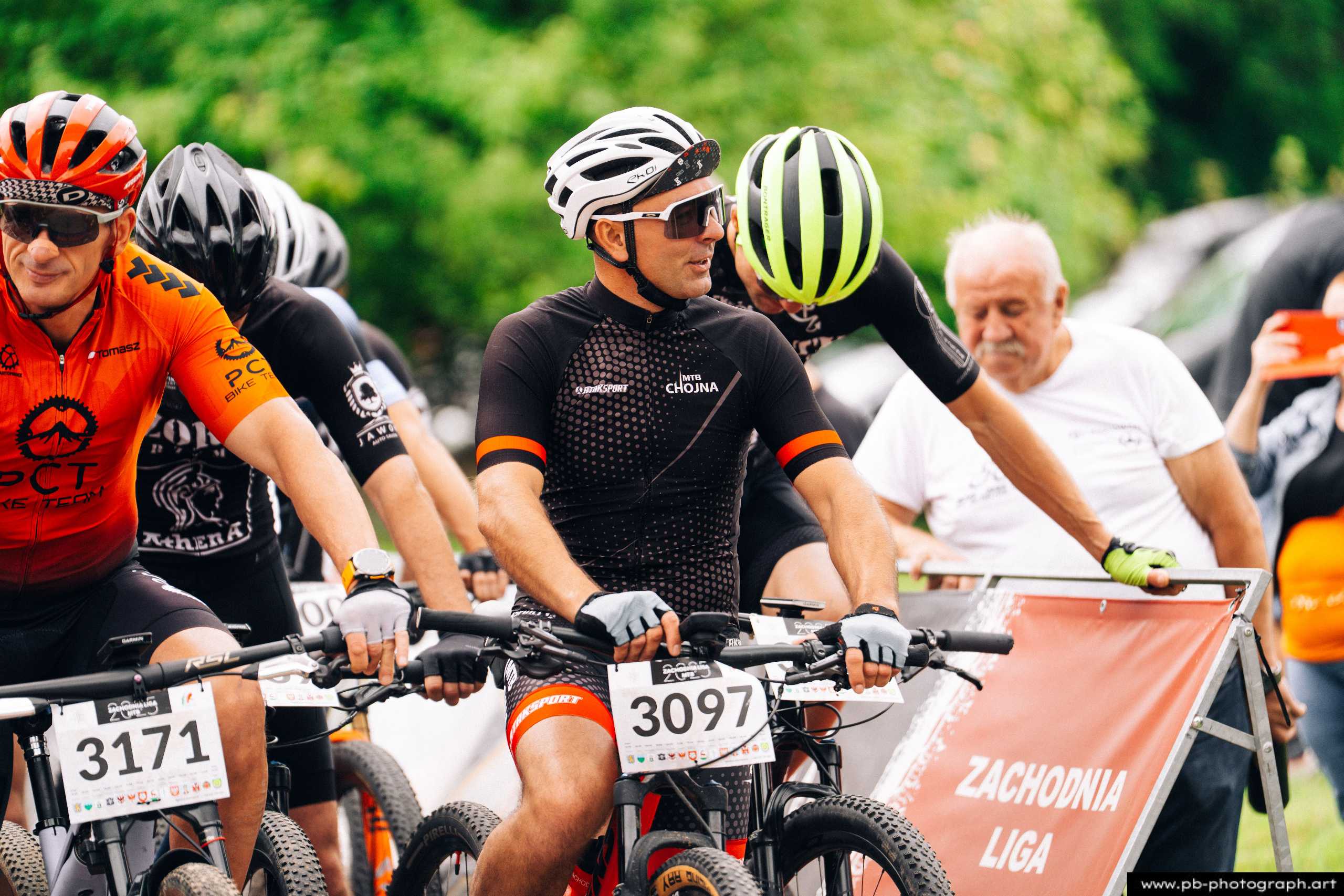 Ujęcie z drona podczas wyścigów MTB w Szczecinie, zawodnicy na starcie, w tle zieleń i kibice.