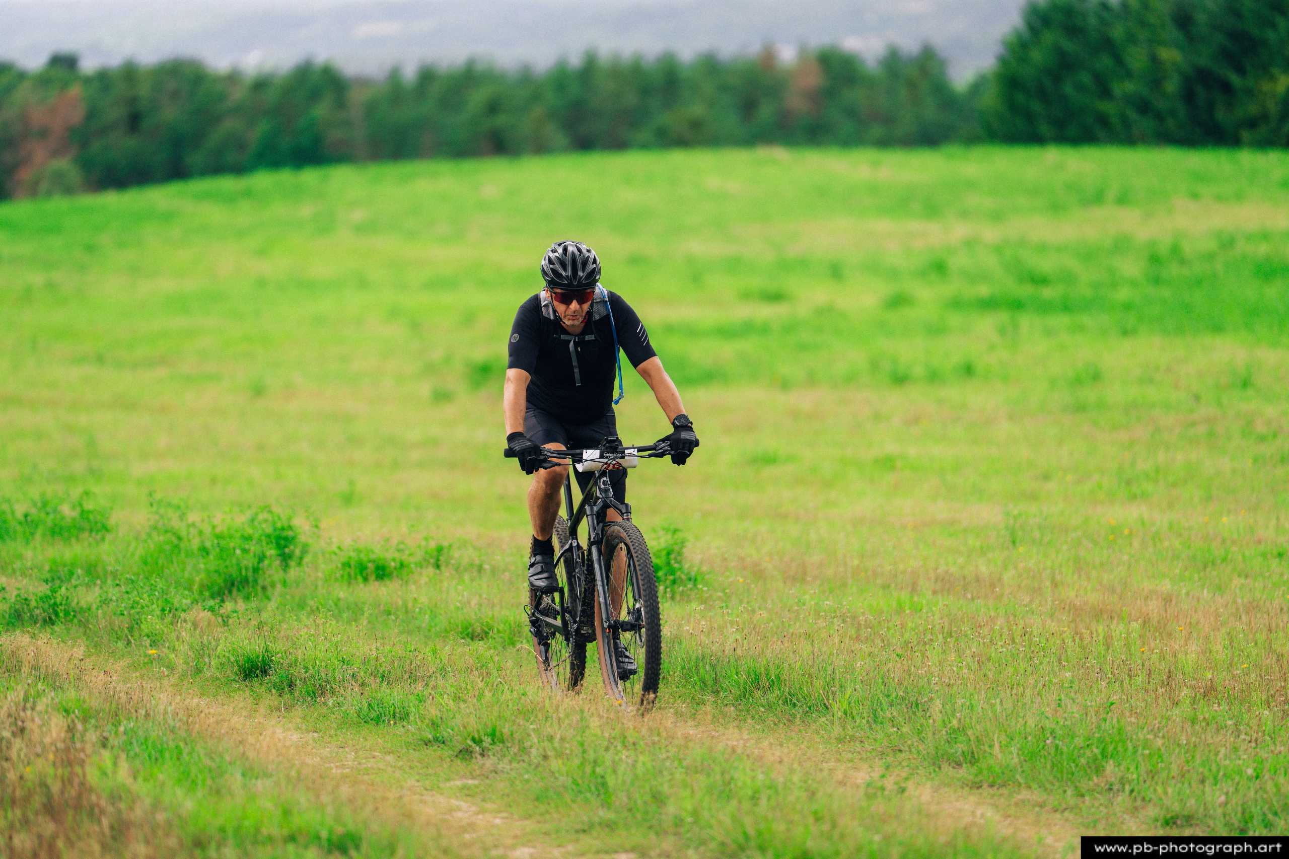 Zawodnik na rowerze górskim pokonuje trawiastą trasę podczas wyścigów MTB w Szczecinie.