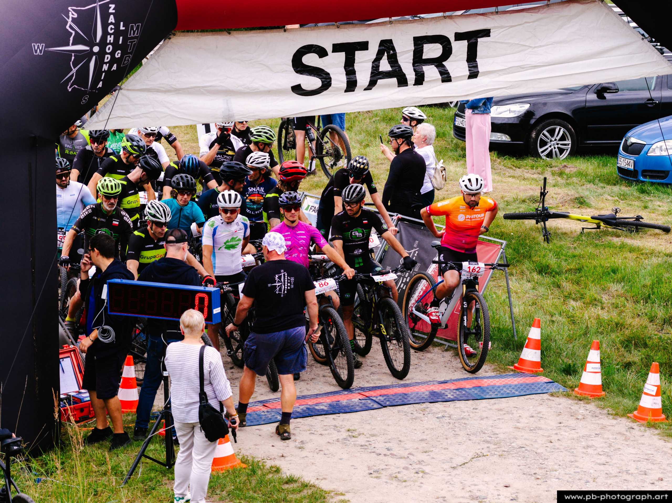 Ujęcie z drona na start wyścigu MTB w Szczecinie, zawodnicy przygotowujący się do rywalizacji pod bramą startową.