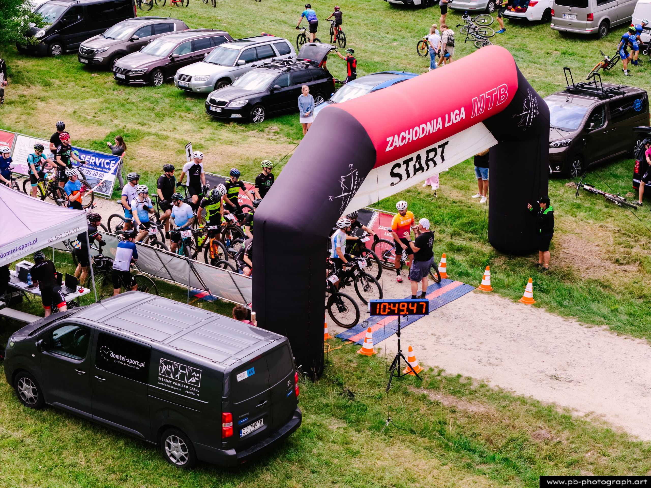 Ujęcie z drona na start wyścigu MTB w Szczecinie, z zawodnikami przygotowującymi się do startu pod łukiem startowym.
