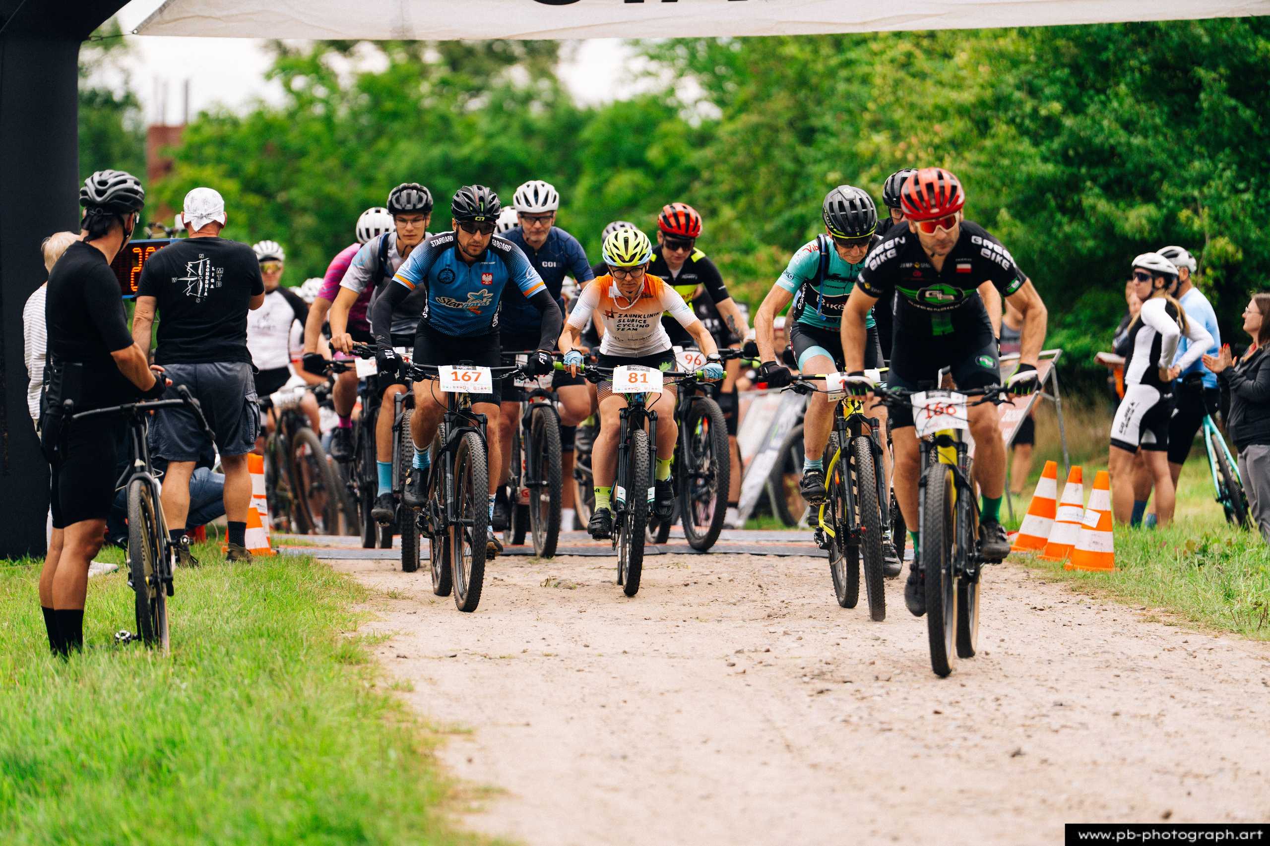 Ujęcie z drona z wyścigu MTB w Szczecinie — zawodnicy na trasie, zbliżający się do mety, w tle kibice.