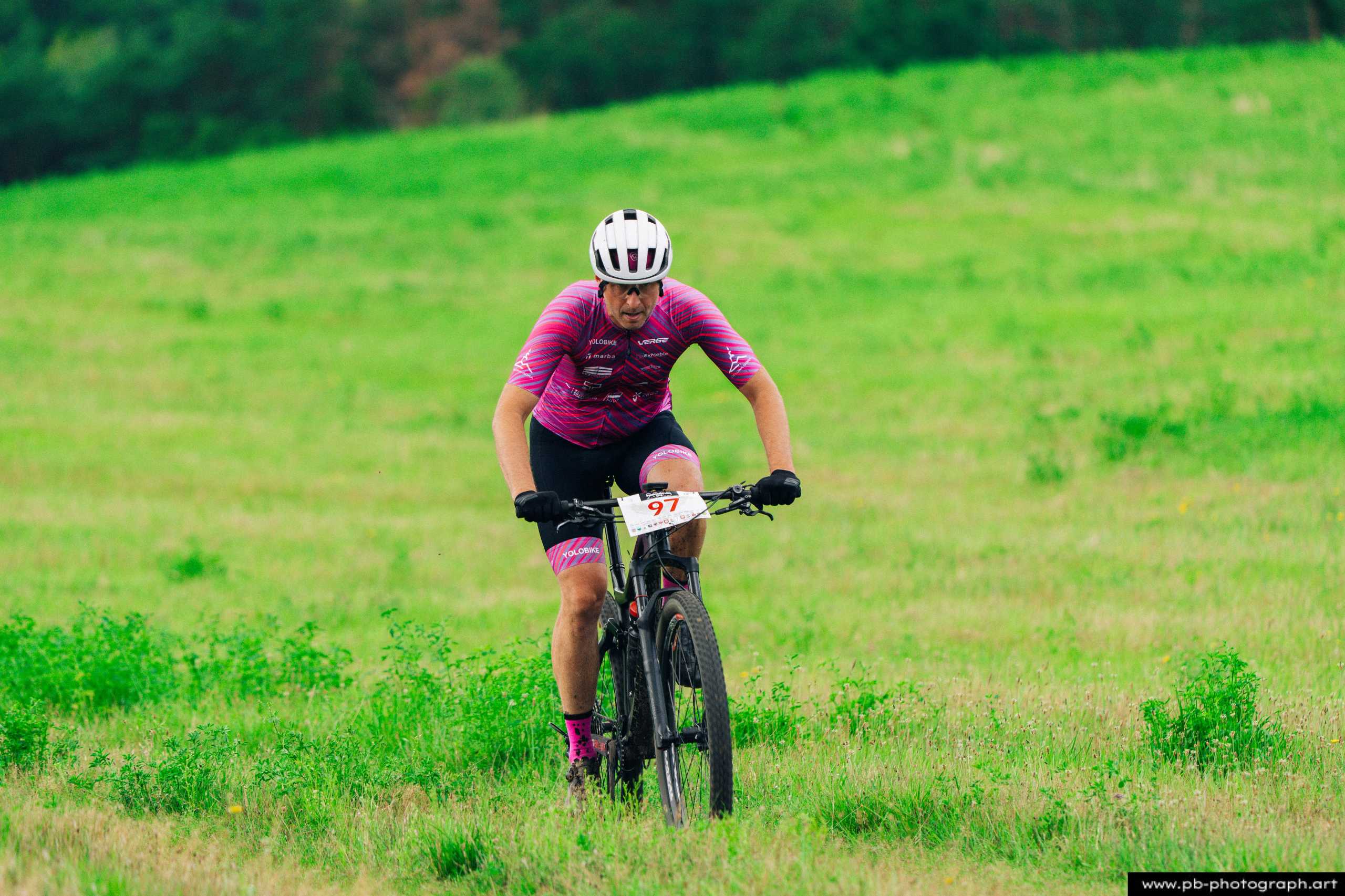 Ujęcie z drona zawodnika MTB w różowym stroju pokonującego zieloną trasę wyścigu w Szczecinie.