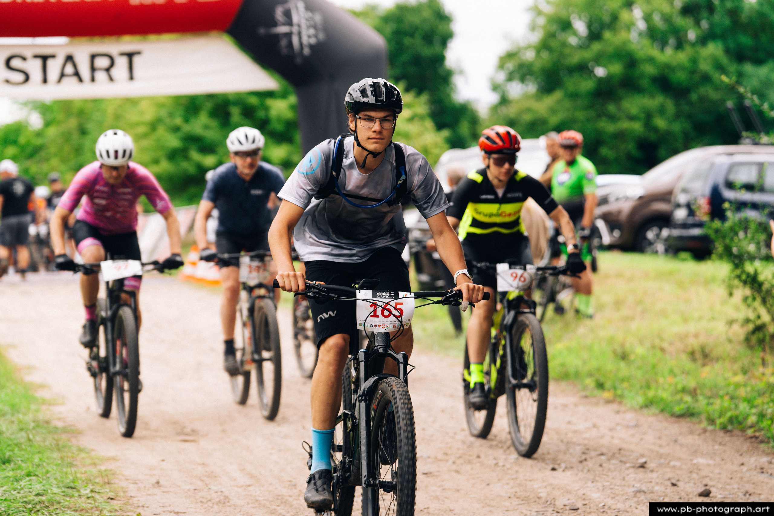 Ujęcie z drona podczas wyścigu MTB w Szczecinie — zawodnicy startujący na trasę z numerami startowymi.