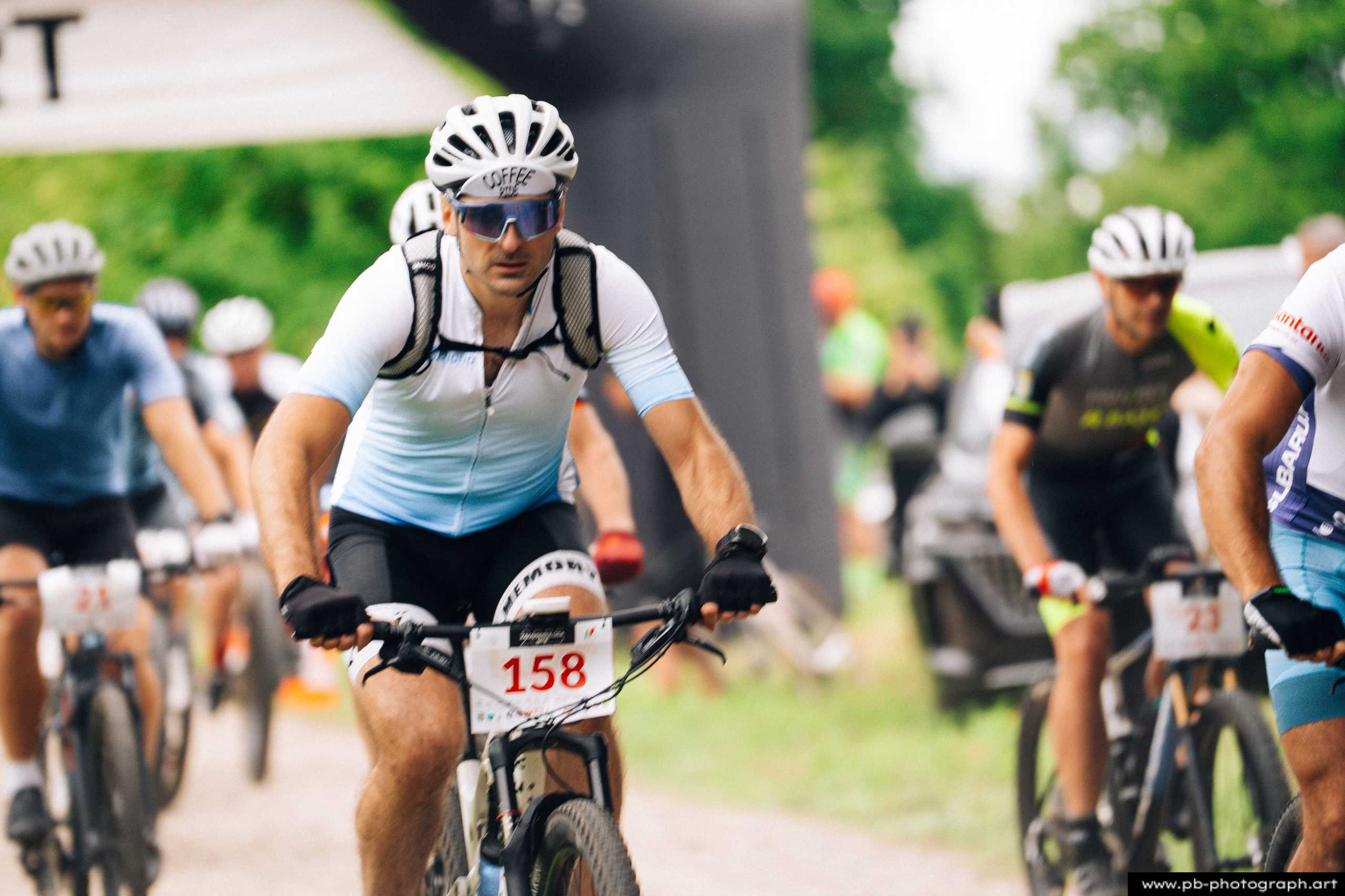Zawodnik na rowerze górskim podczas wyścigu MTB w Szczecinie, zbliżenie na trasę i konkurentów w tle.