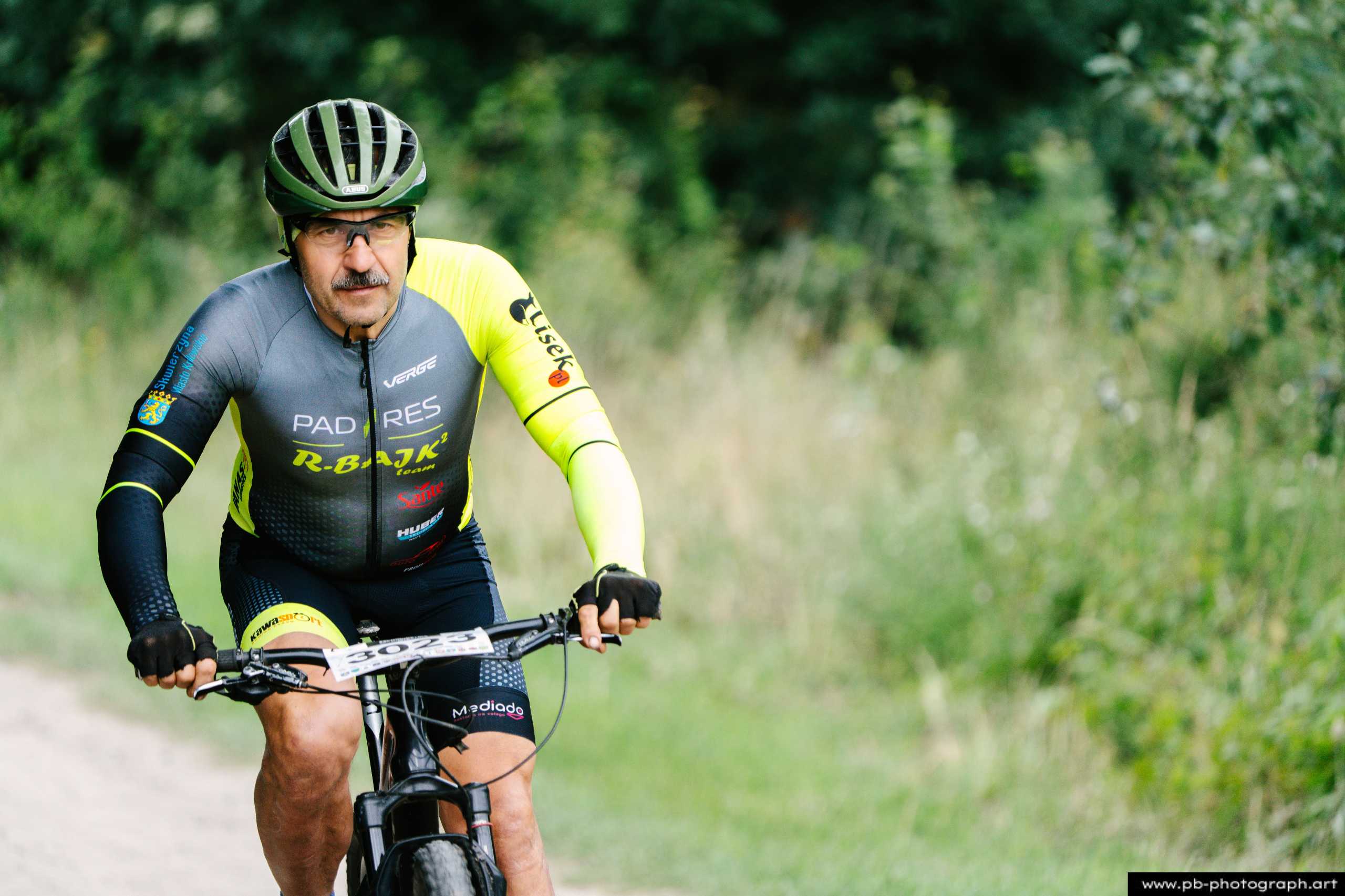 Zawodnik na rowerze górskim podczas wyścigu MTB w Szczecinie, zbliżenie na twarz i detale stroju.