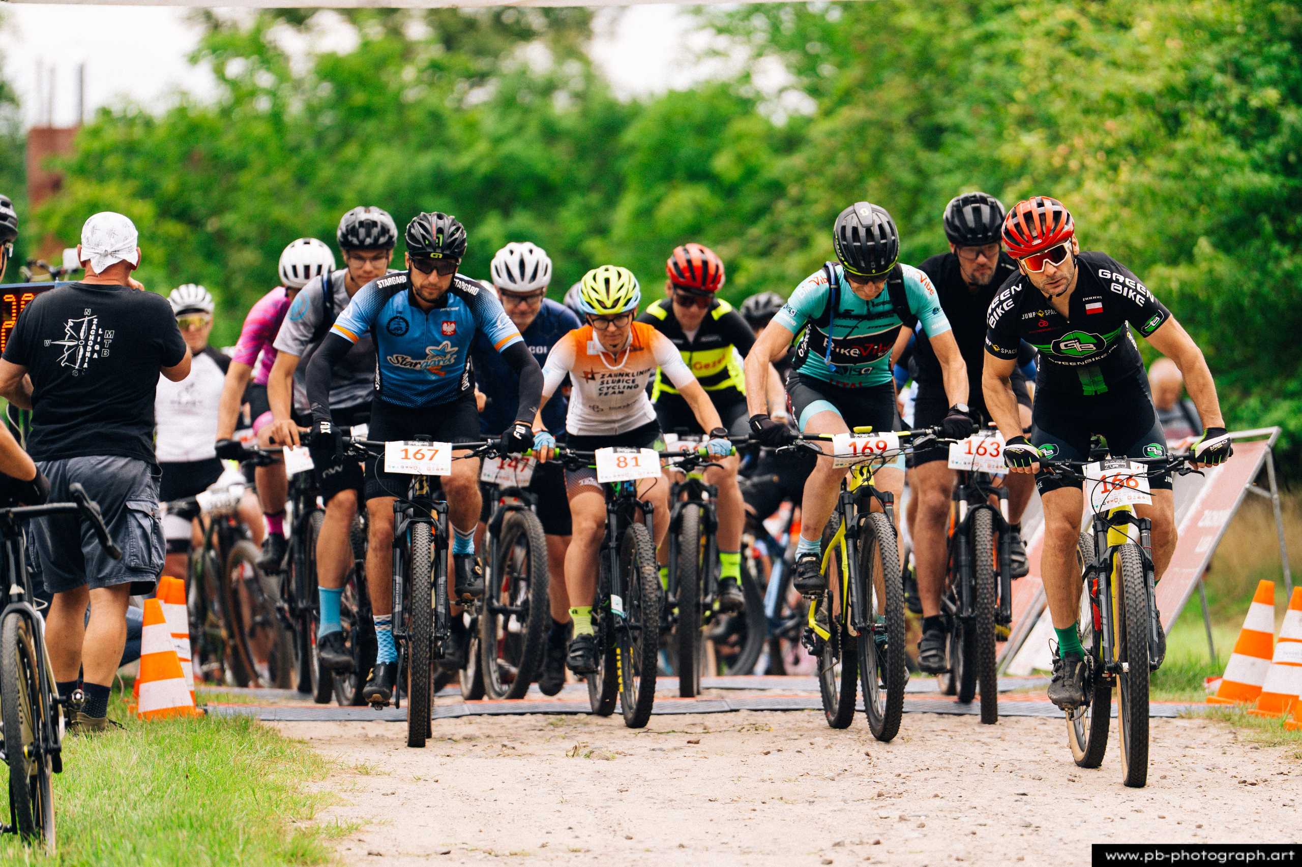 Ujęcie z drona podczas wyścigu MTB w Szczecinie, zawodnicy na trasie wśród zieleni, z numerami na rowerach.