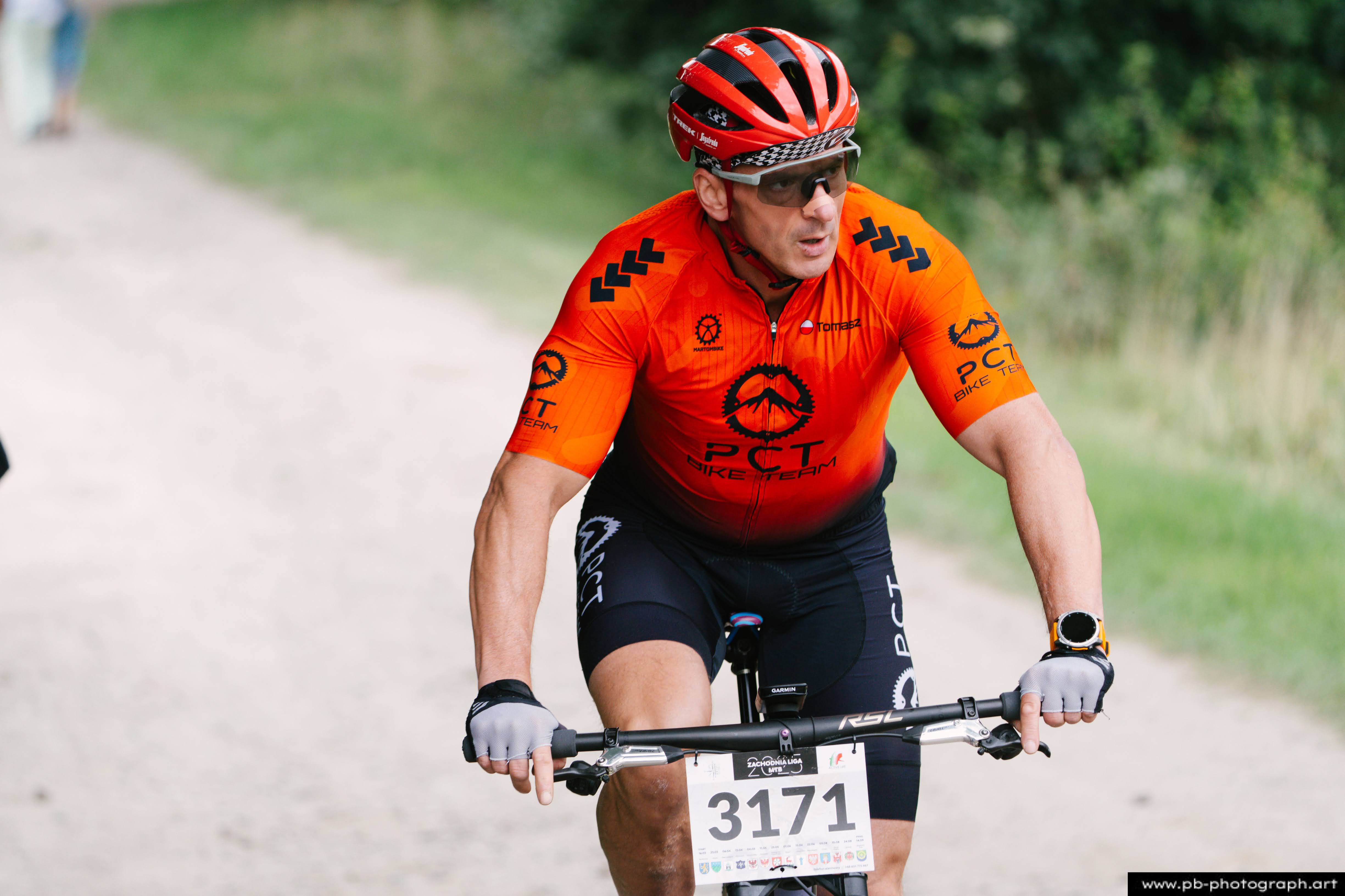Zawodnik w pomarańczowej koszulce na rowerze podczas wyścigu MTB w Szczecinie.