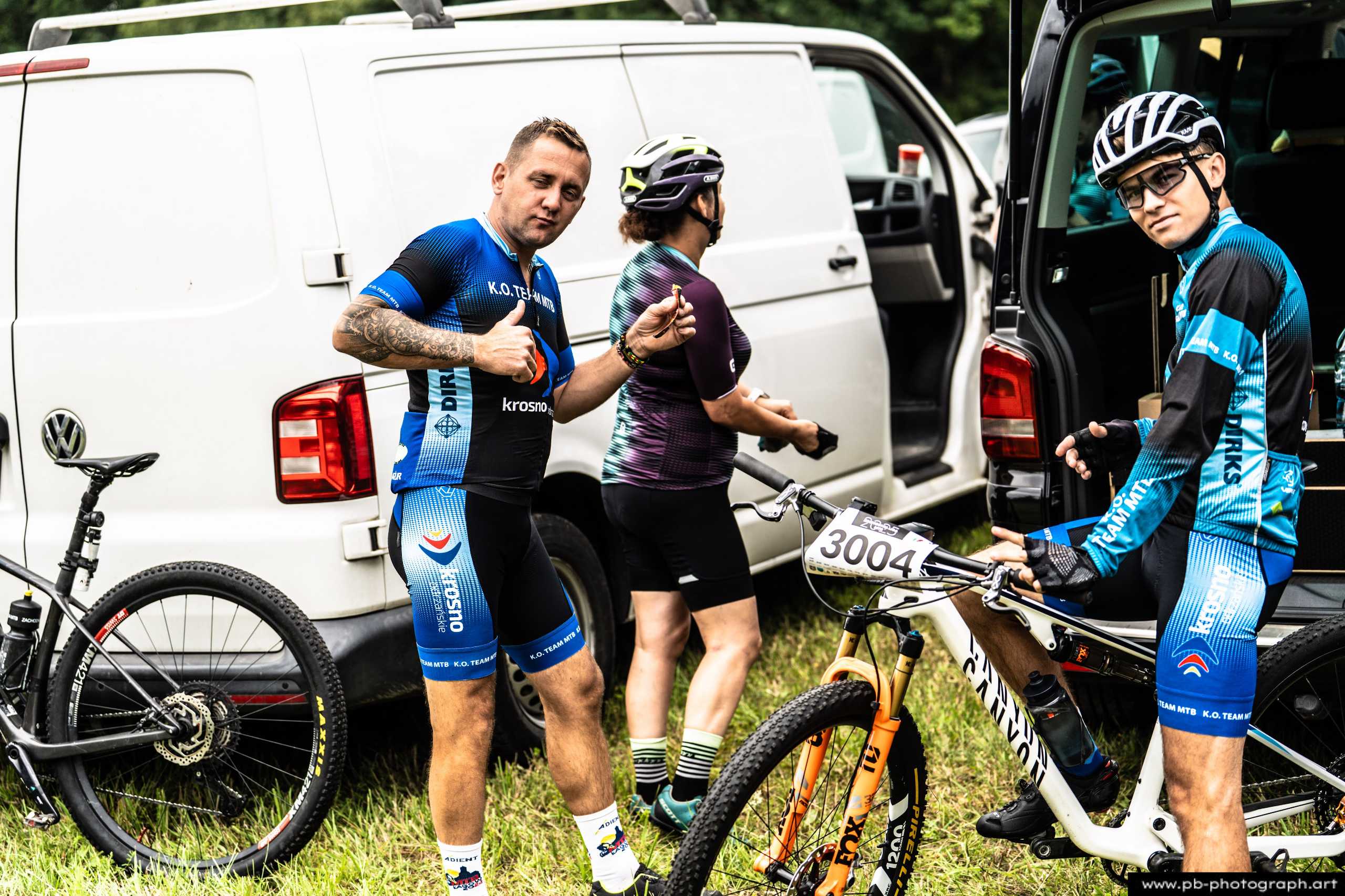 Zawodnicy przygotowujący się do wyścigu MTB obok samochodów, w strojach sportowych w Szczecinie.