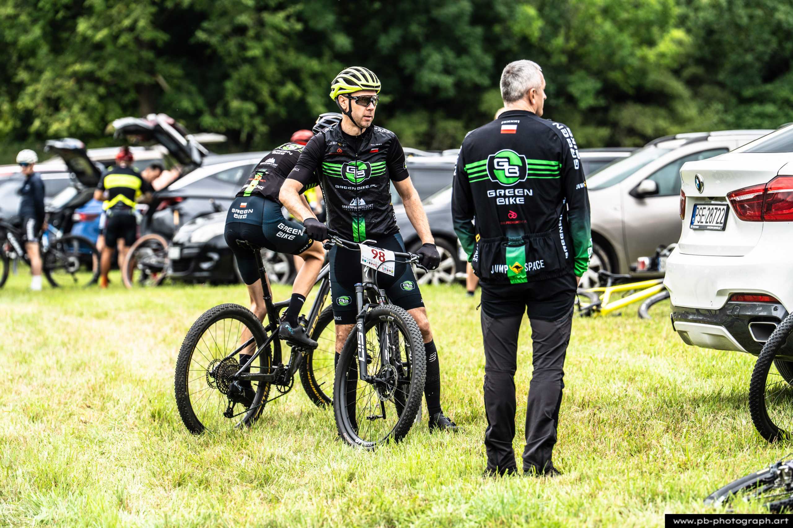 Zawodnicy MTB przygotowujący się do wyścigu na tle samochodów w Szczecinie.