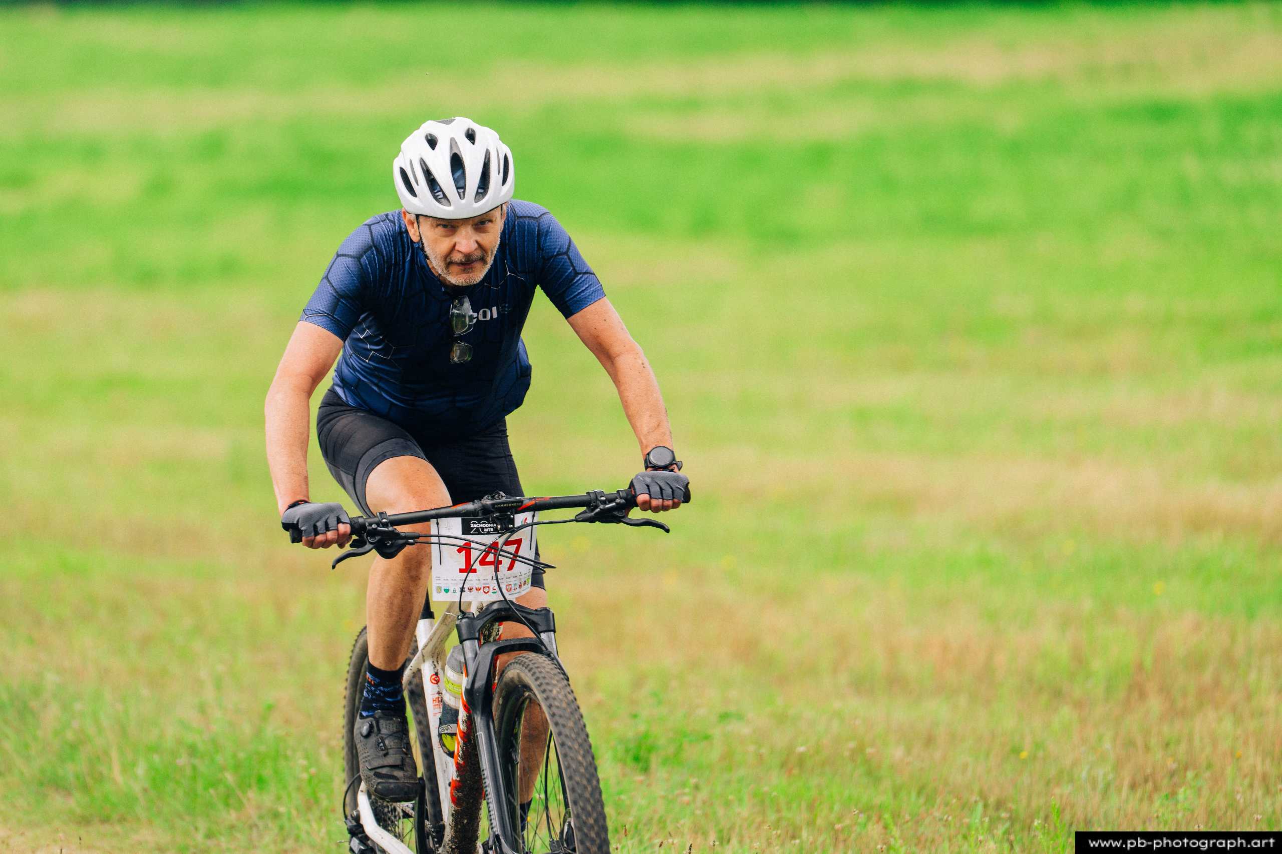 Zawodnik na rowerze górskim podczas wyścigu MTB w Szczecinie, w pełnym skupieniu pokonuje trasę w terenie.