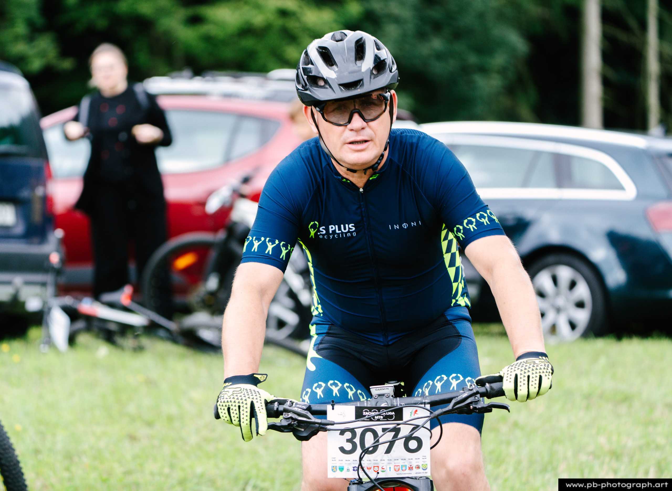Zawodnik na rowerze górskim podczas wyścigu MTB w Szczecinie, w tle samochody i zieleń.