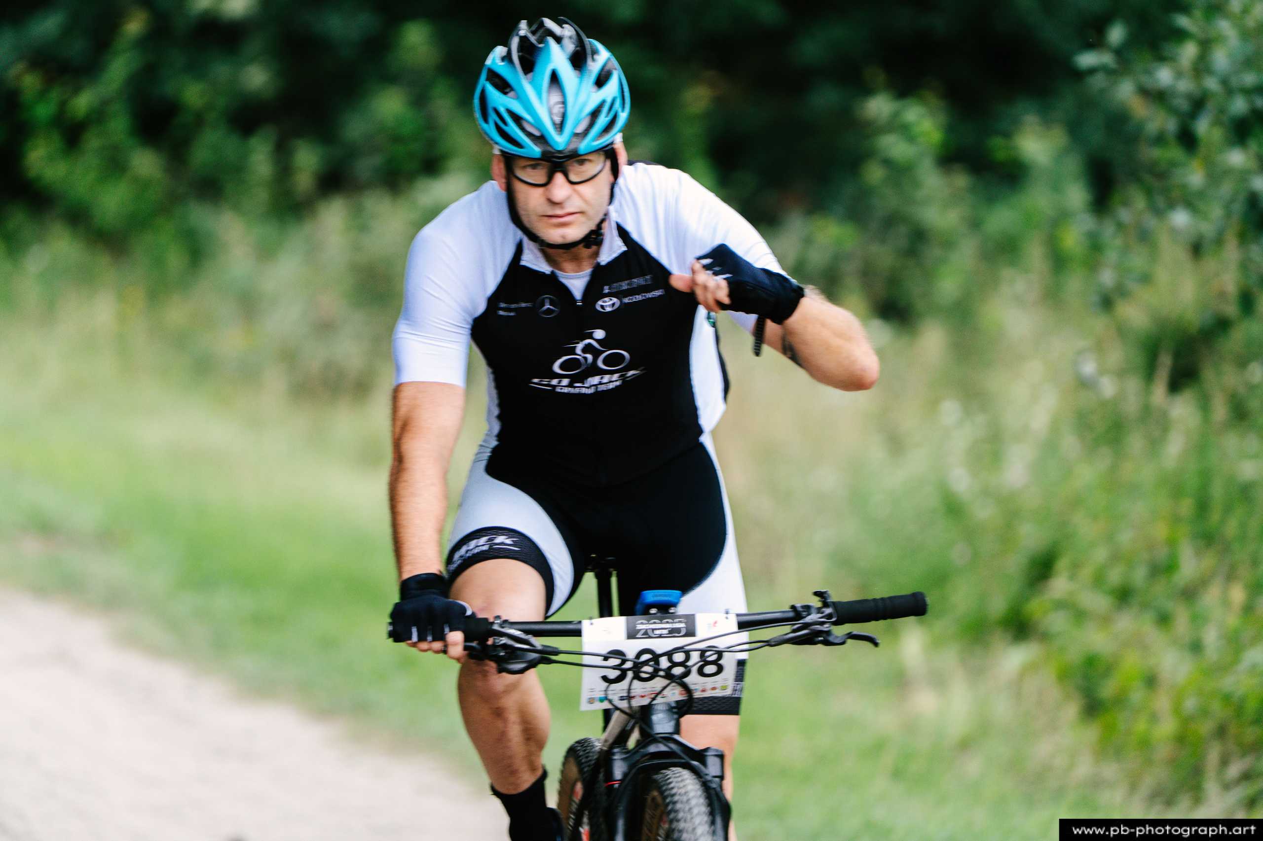 Zawodnik MTB w akcji podczas wyścigu w Szczecinie, z widoczną trasą i zielonym tłem.