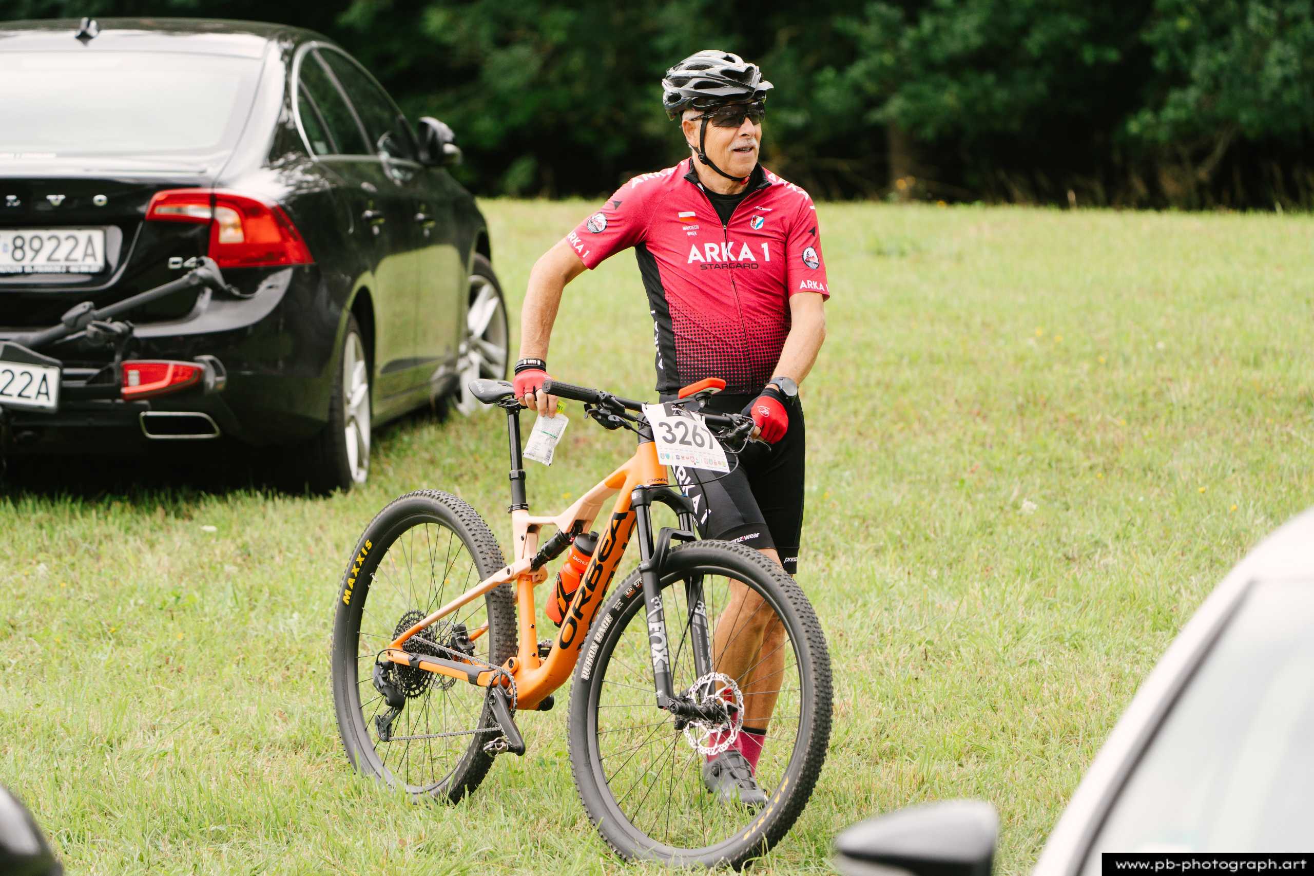 Zawodnik z rowerem górskim w czerwonym stroju, przygotowujący się do wyścigu MTB w Szczecinie.
