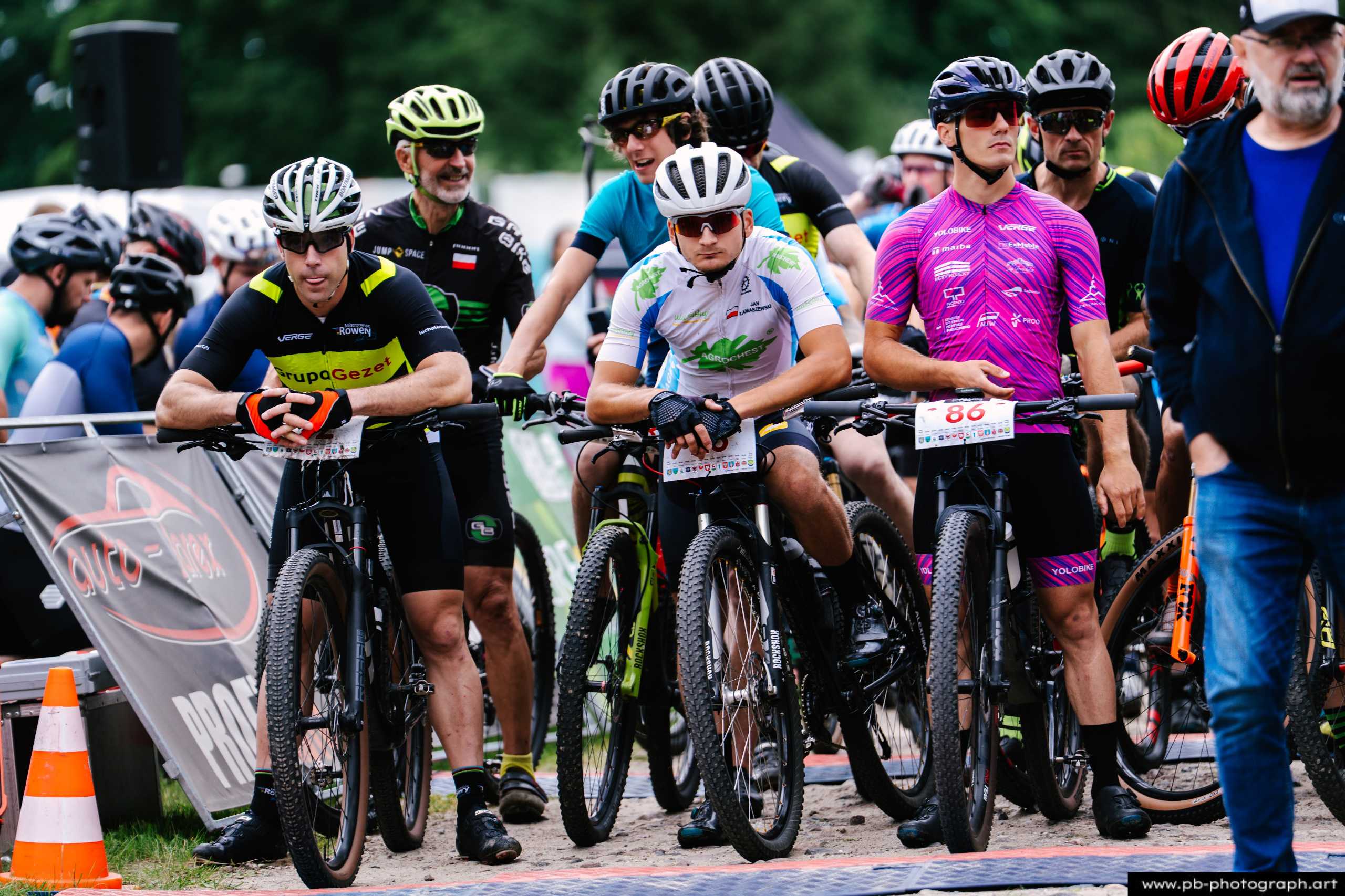 Zawodnicy na starcie wyścigu MTB w Szczecinie, gotowi do rywalizacji, w tle widoczne banery i publiczność.